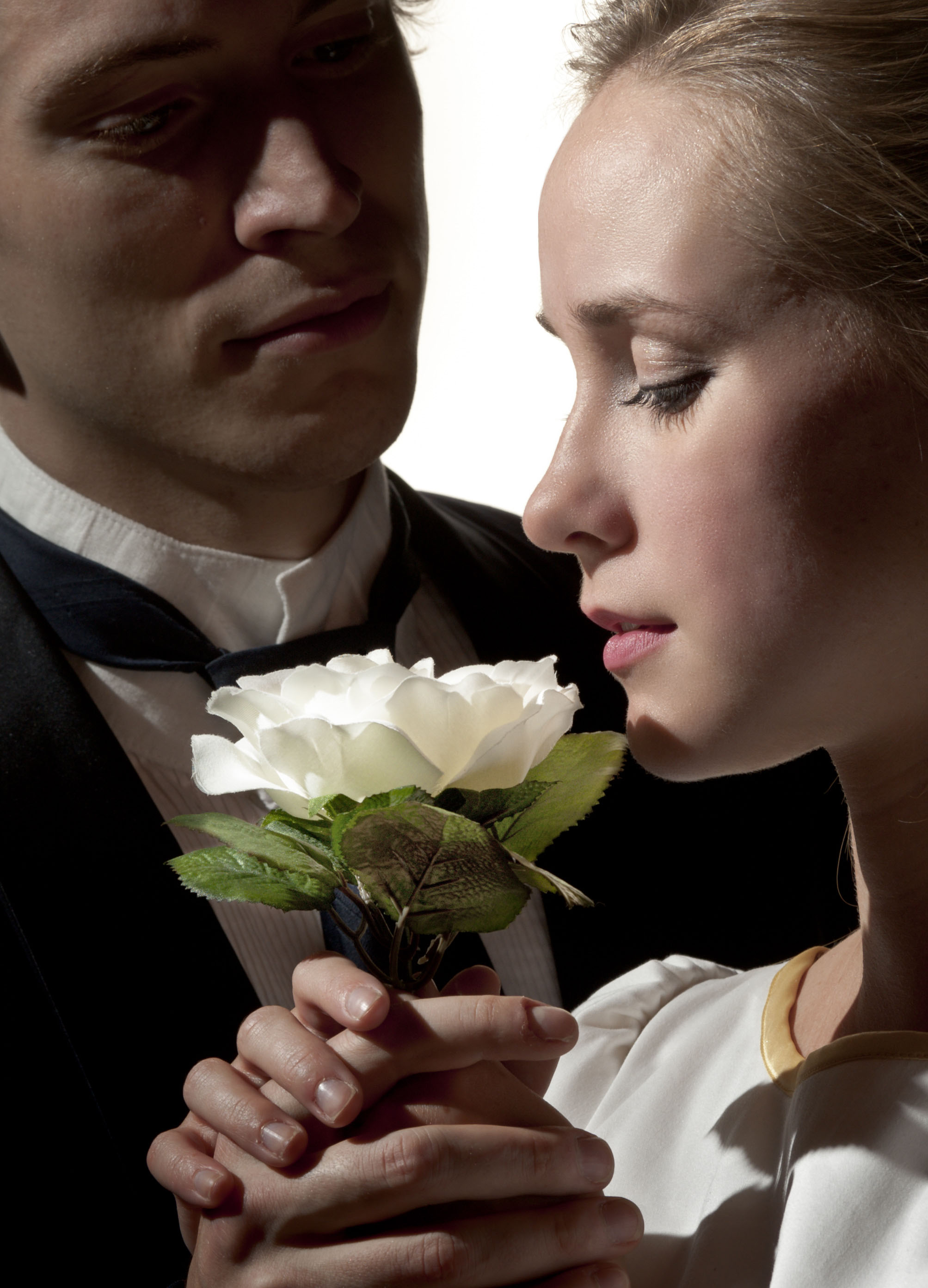 Woman smelling a flower that a man is handing her. 