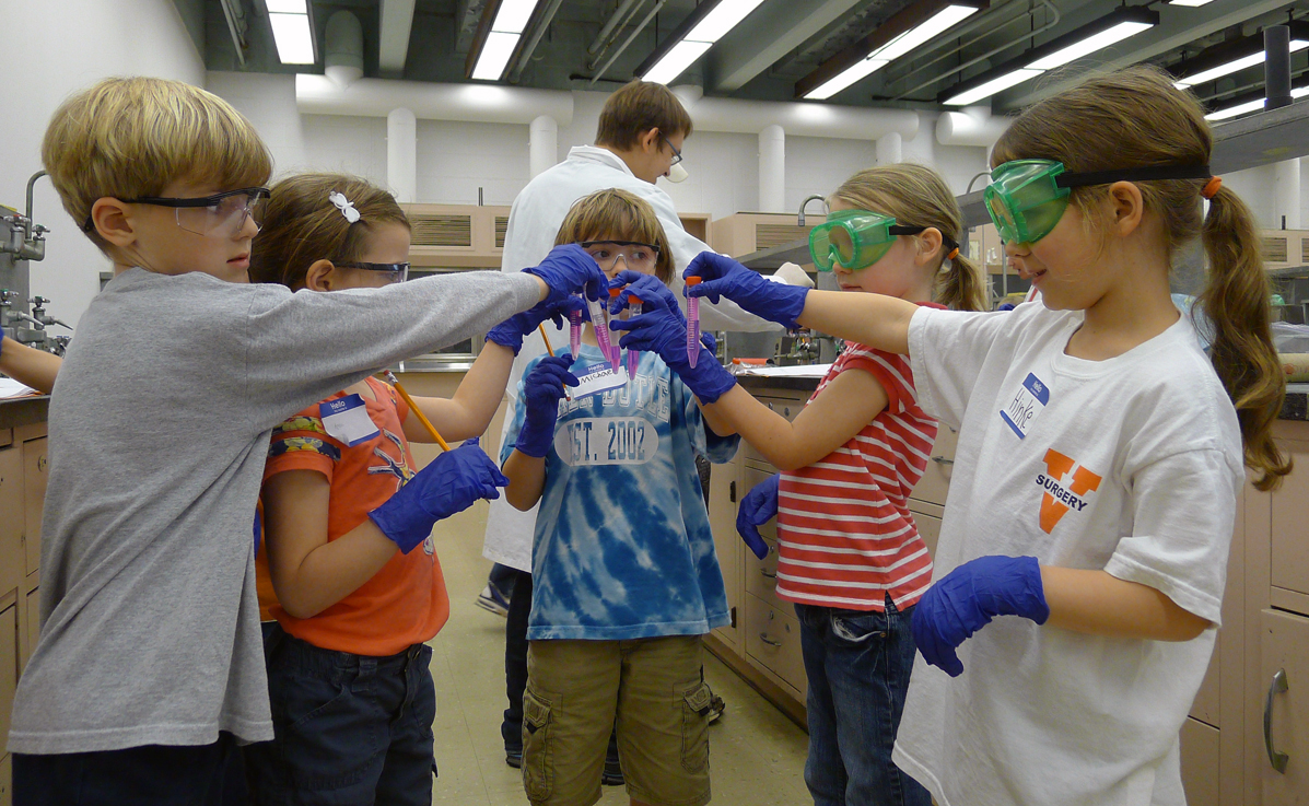 Children in a lab performing an infectious disease simulation with test tubes