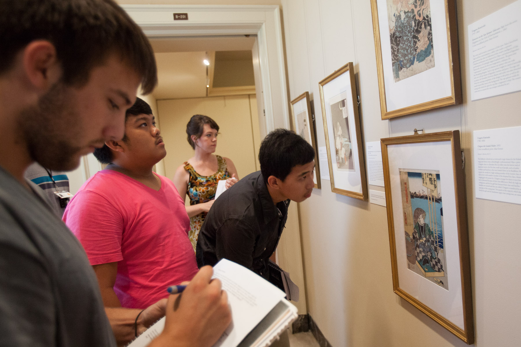 Students observing art work in a gallery and write notes