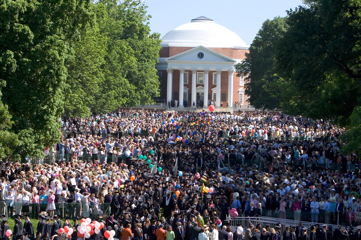 The Lawn full of graduates and families as the graduates walk to their seats with the Rotunda in the background