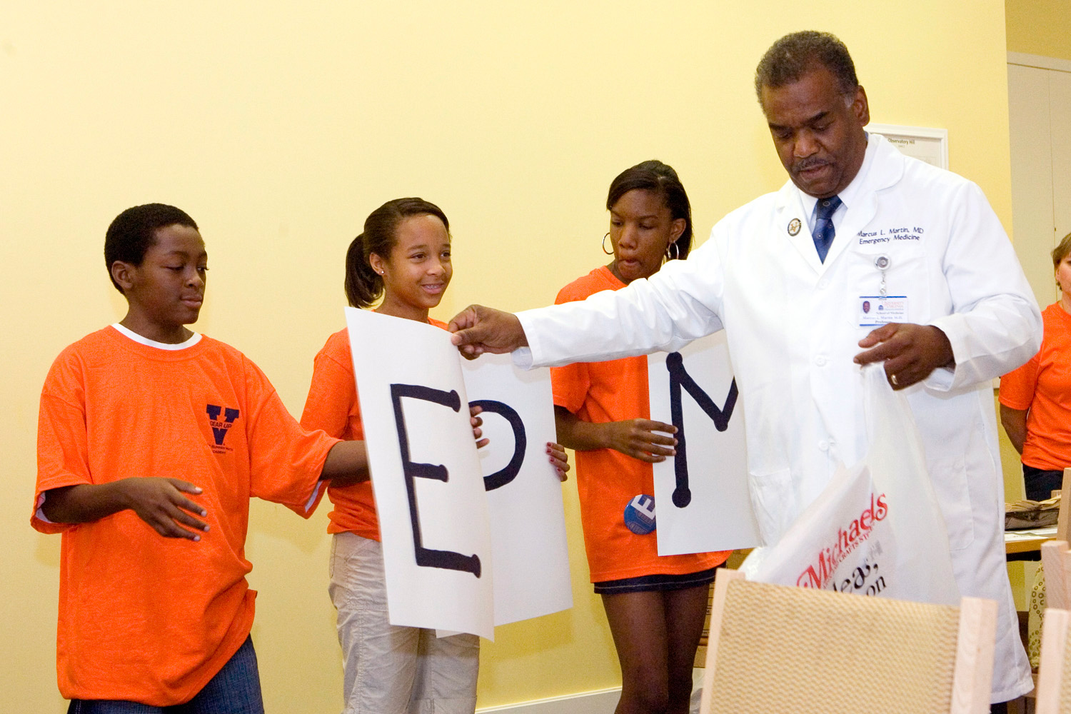Dr. Marcus Martin hands letters to small children who are standing in a line