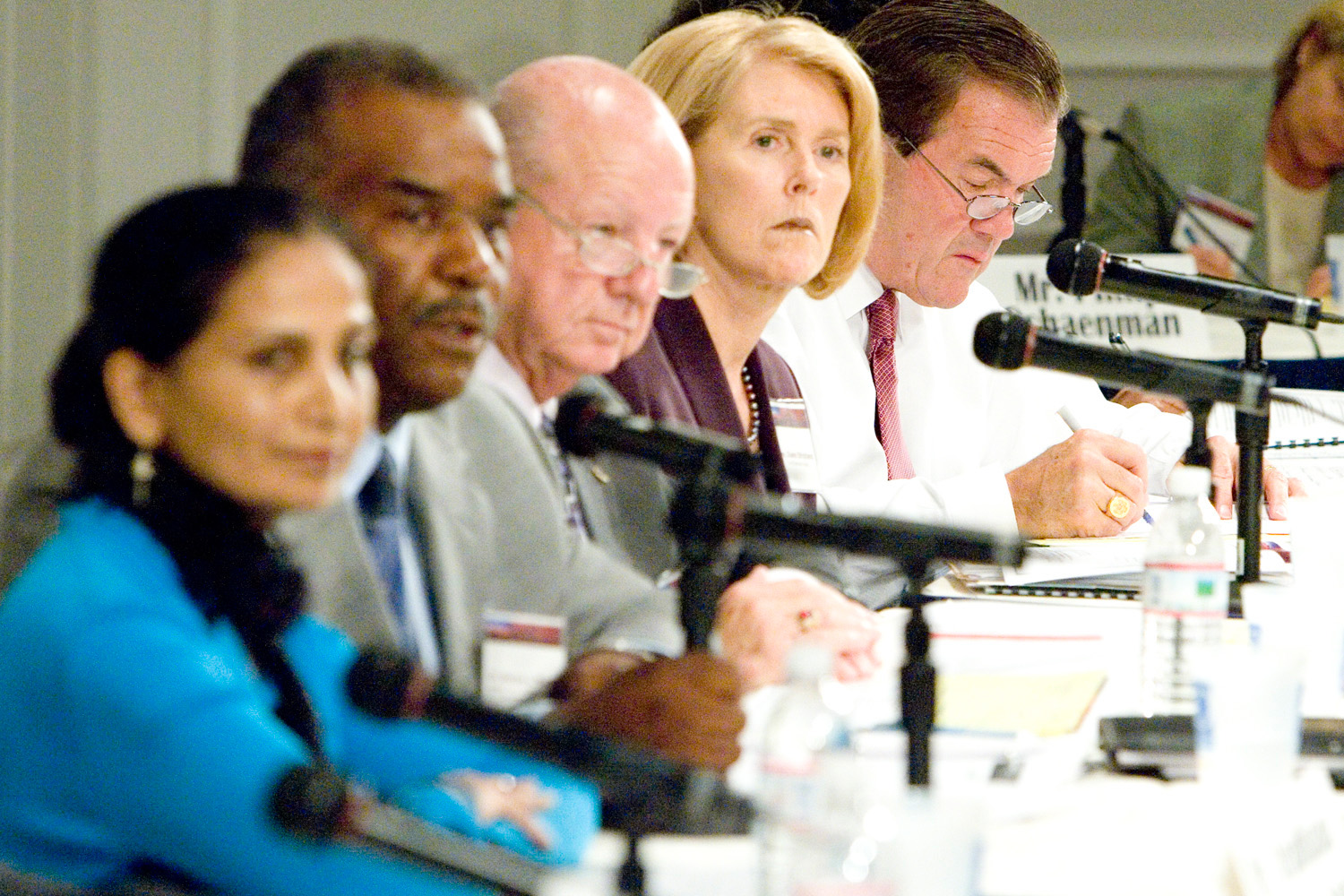 Review panel sitting at microphones listening to testimony