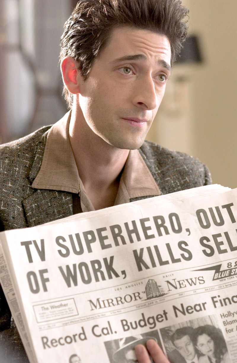 Adrien Brody holds a newspaper during a scene in a movie