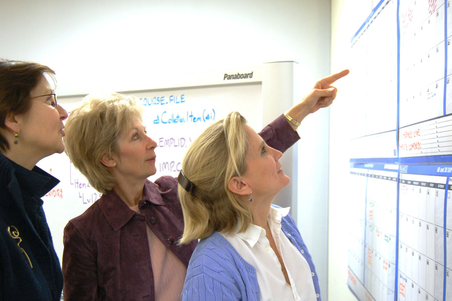 Susan Barr, Marianne Kosiewicz and Tracy Pettit examine a calendar on a wall