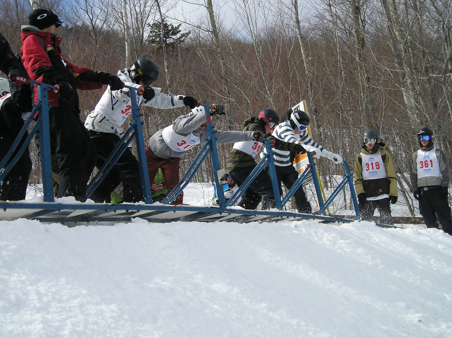 Snow boarders in the gates preparing for a race to start