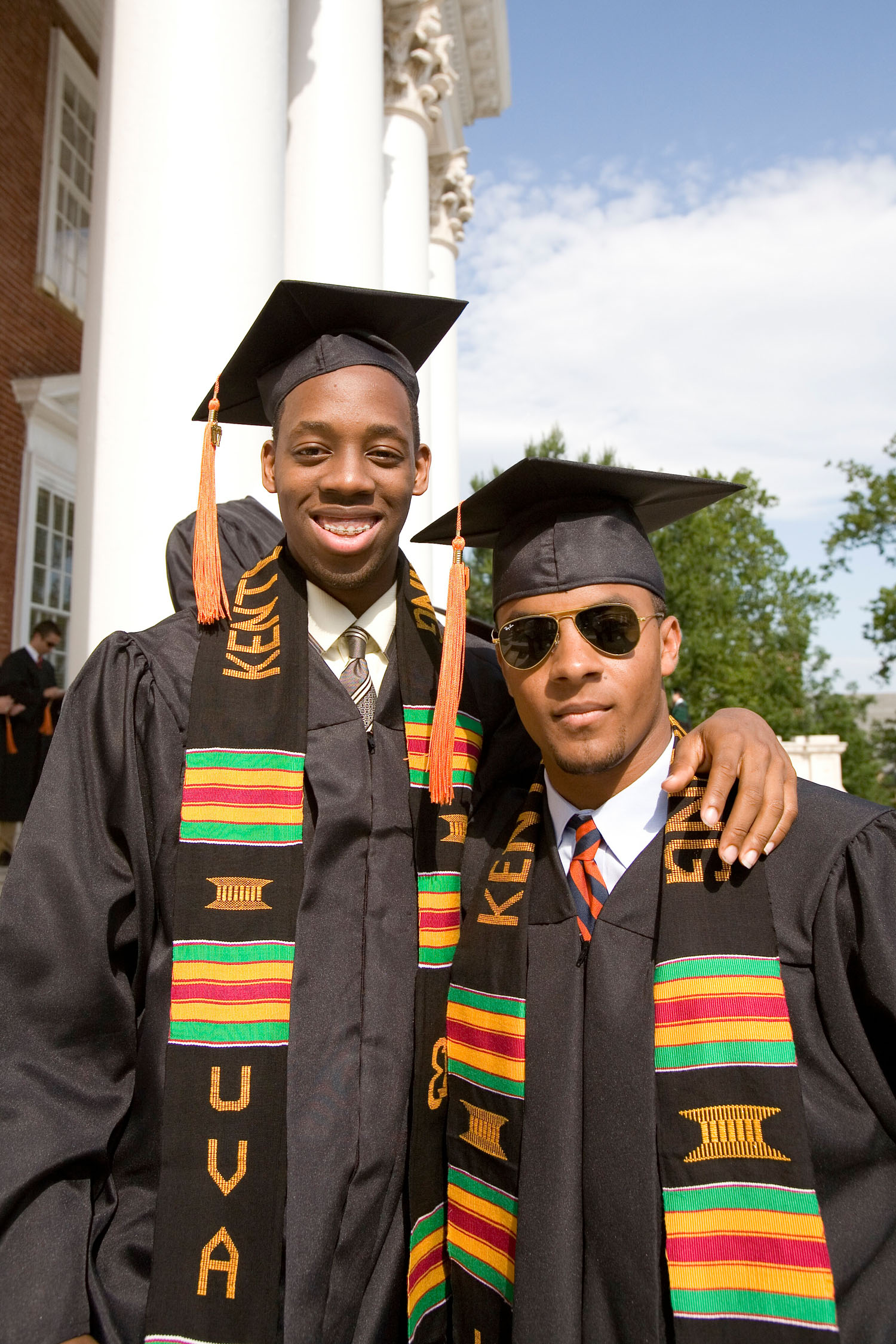 Two African American students stand next to each other in Graduation attire at the Donning of the Kente ceremony