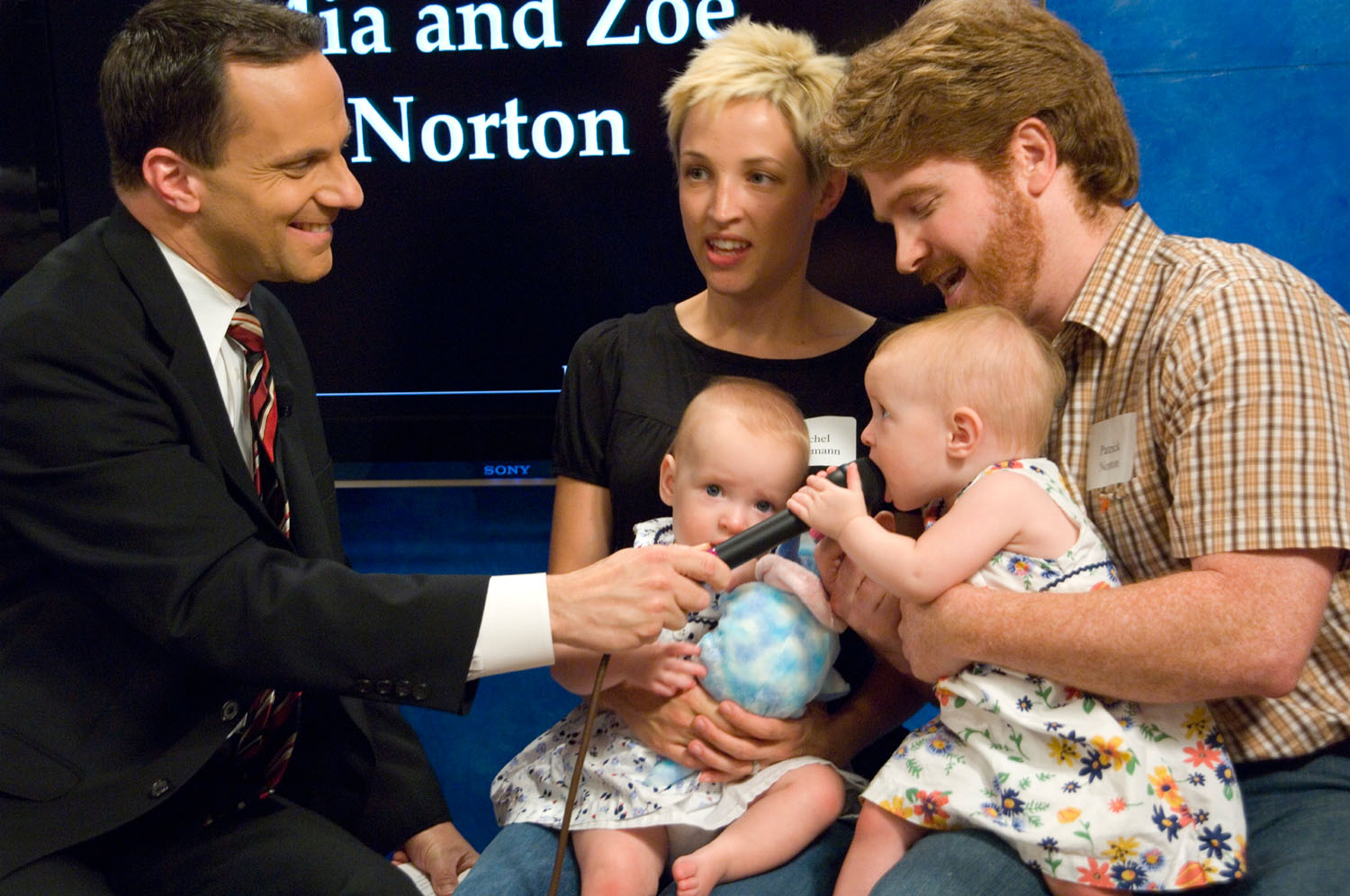  Steve Rappaport interviewing the Norton family with their twin babies.  One of the babies is trying to eat the microphone