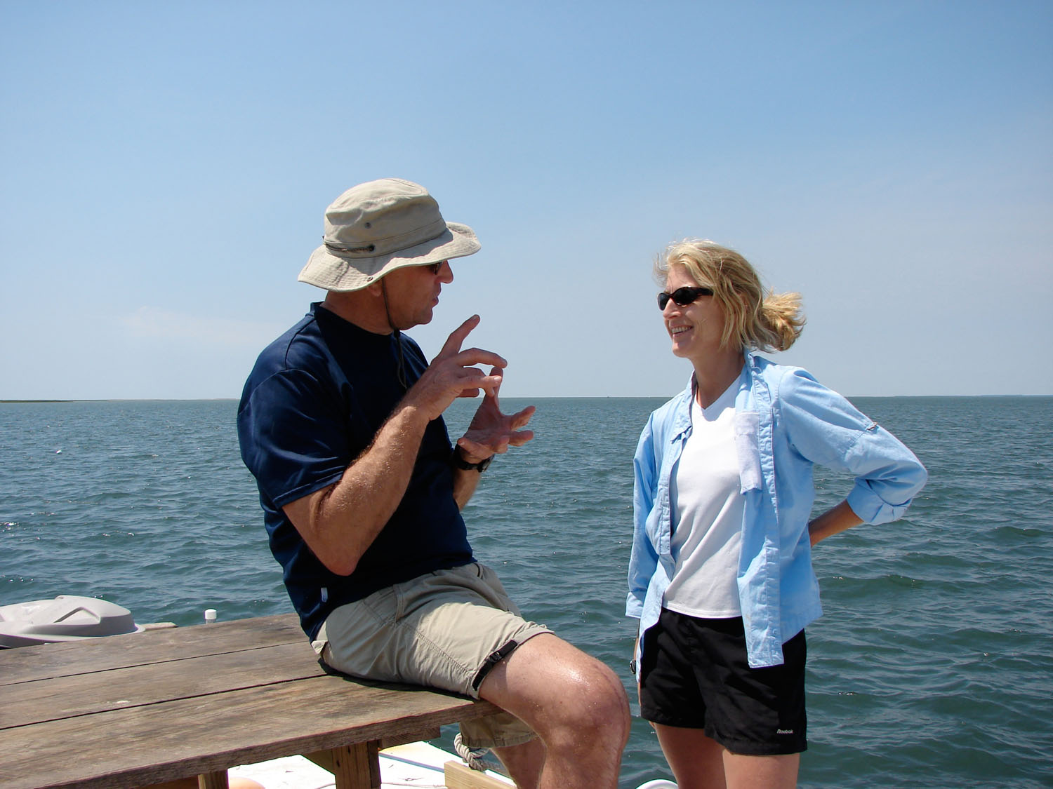 Karen McGlathery, right, talks to Bob Orth, left while standing on a pier at the ocean