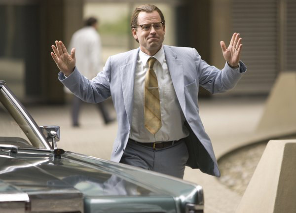 Greg Kinnear walking to a car during a scene for a movie
