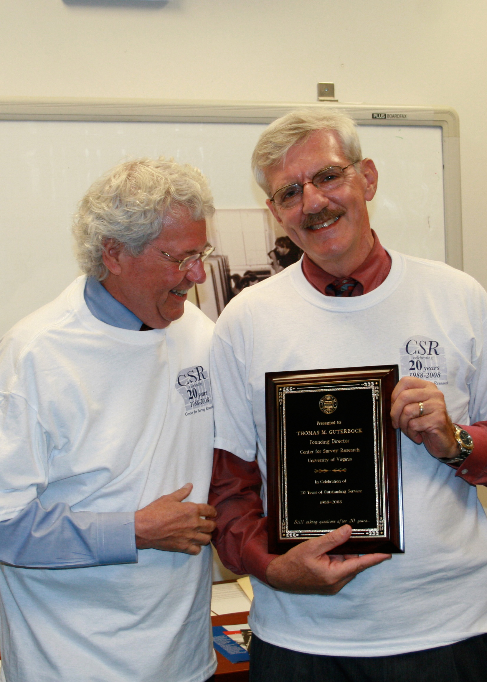 Two men wearing CSR t-shirts and holding a plaque