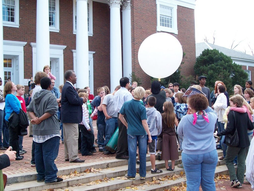Crowd gathered outside of a UVA building releasing a big white weather balloon