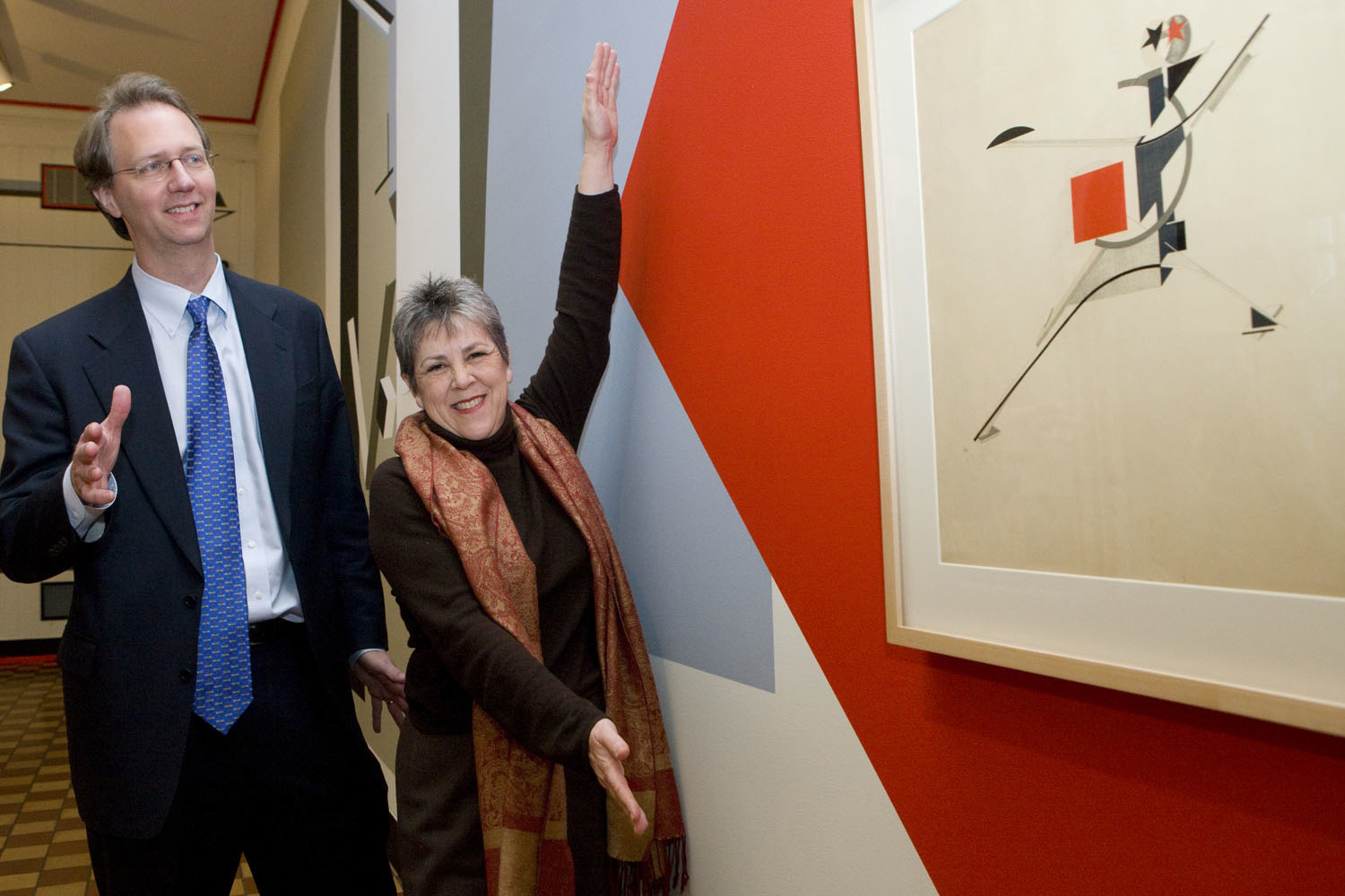 Tom Skalak and Beth Turner show off a painting hanging on a wall