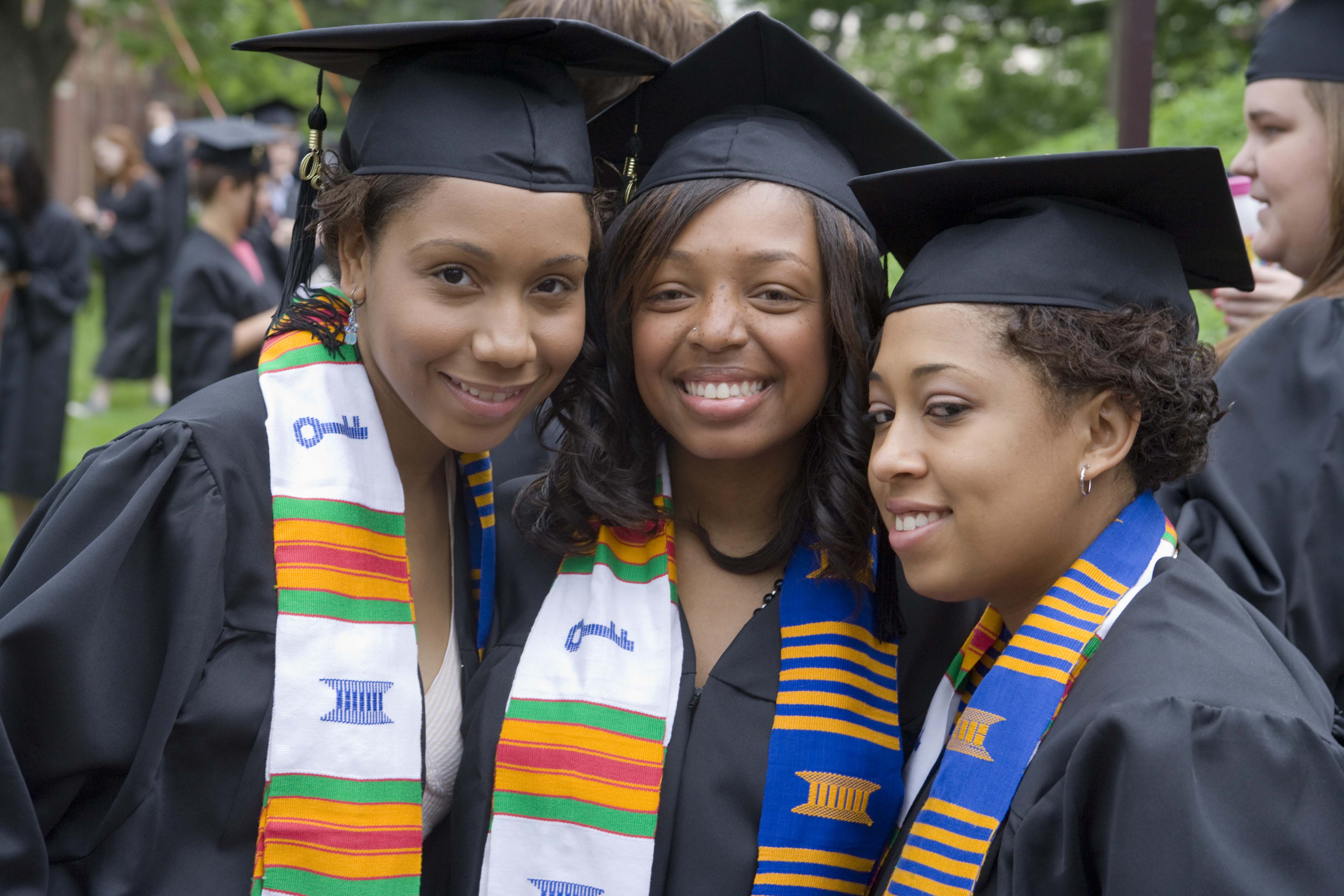 UVA graduates stand together in cap and gown smiling for the camera
