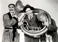 Three people standing.  Two of them are holding a sousaphone. Black and white image 