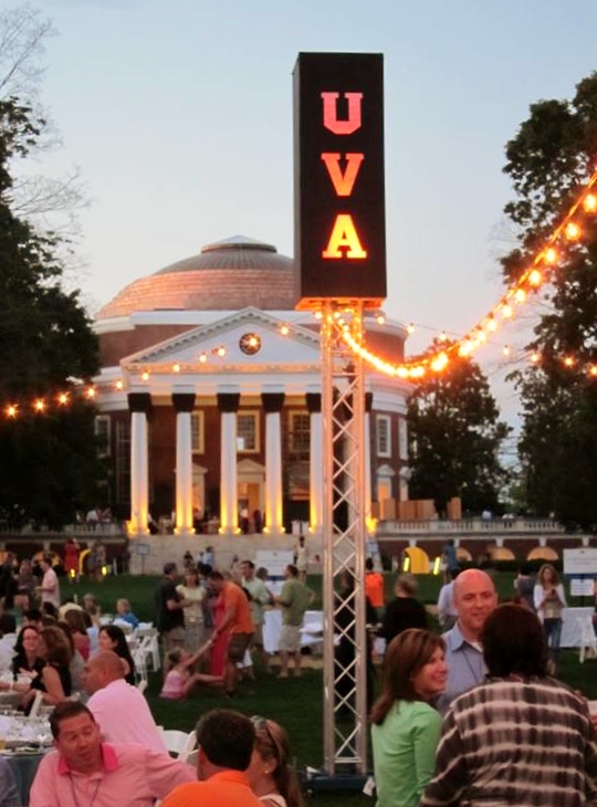 People gathered on a lit up lawn for dinner
