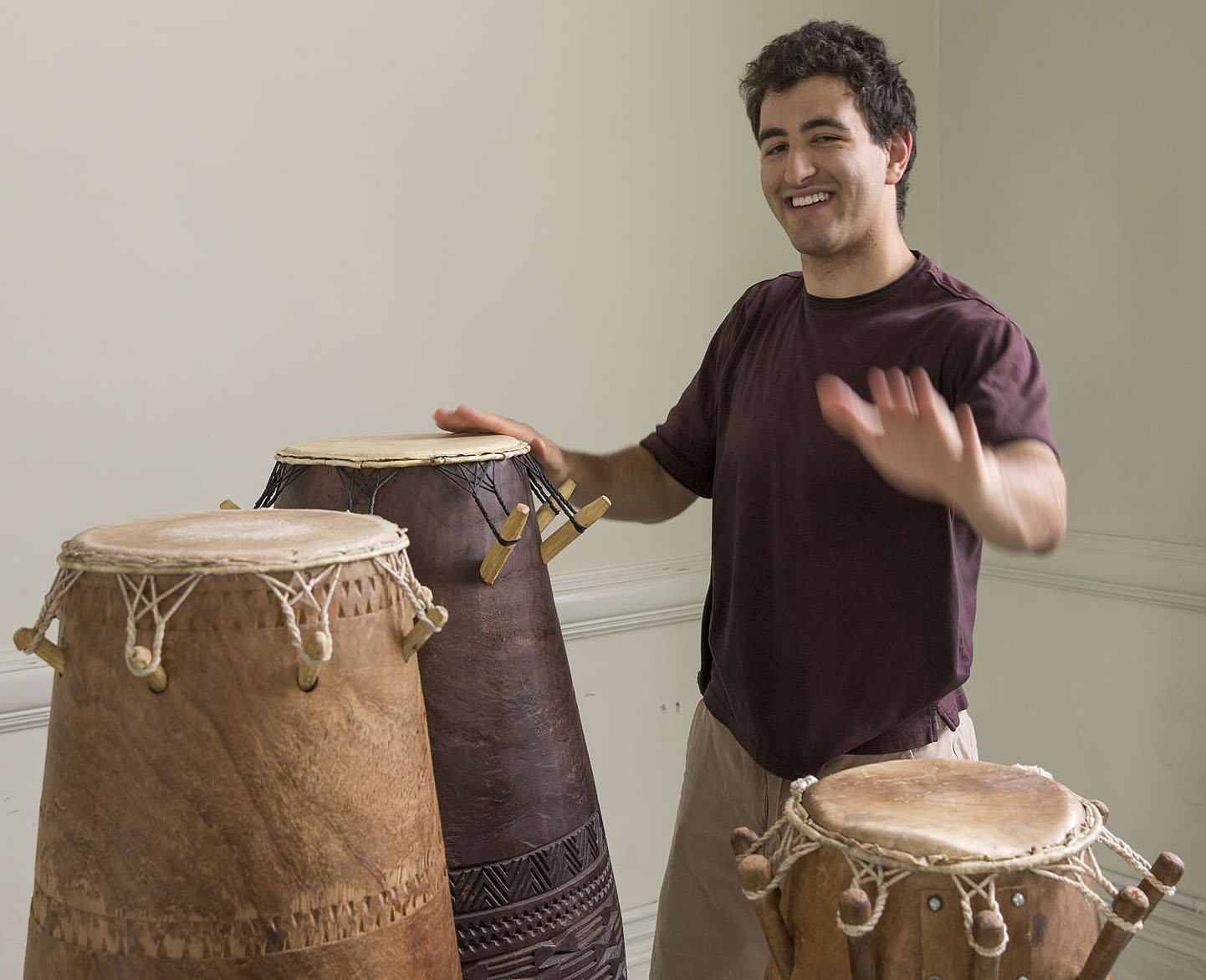 Alan Brody playing African drums while smiling at the camera