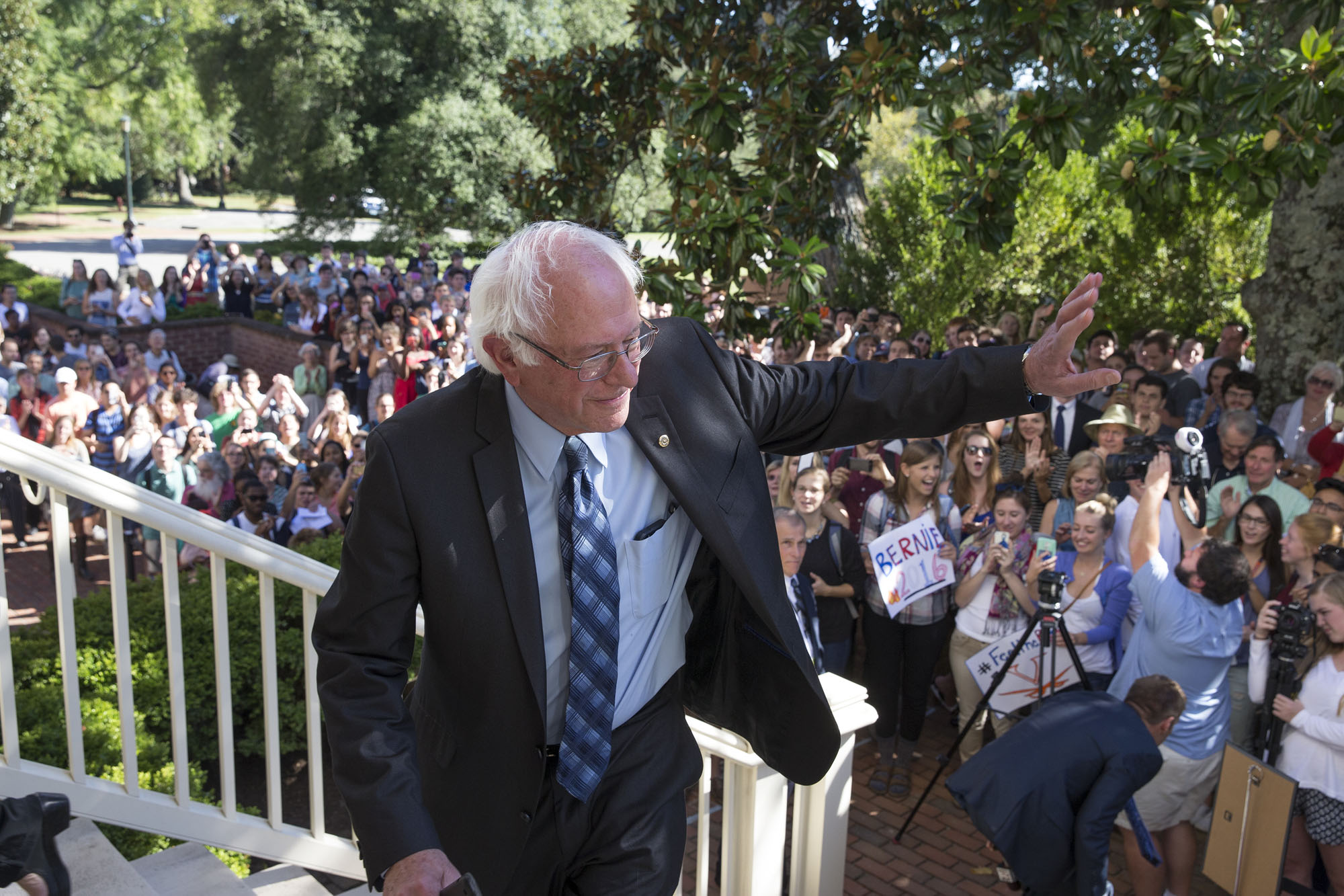 Bernie Sanders walking up steps waiving at a crowd below