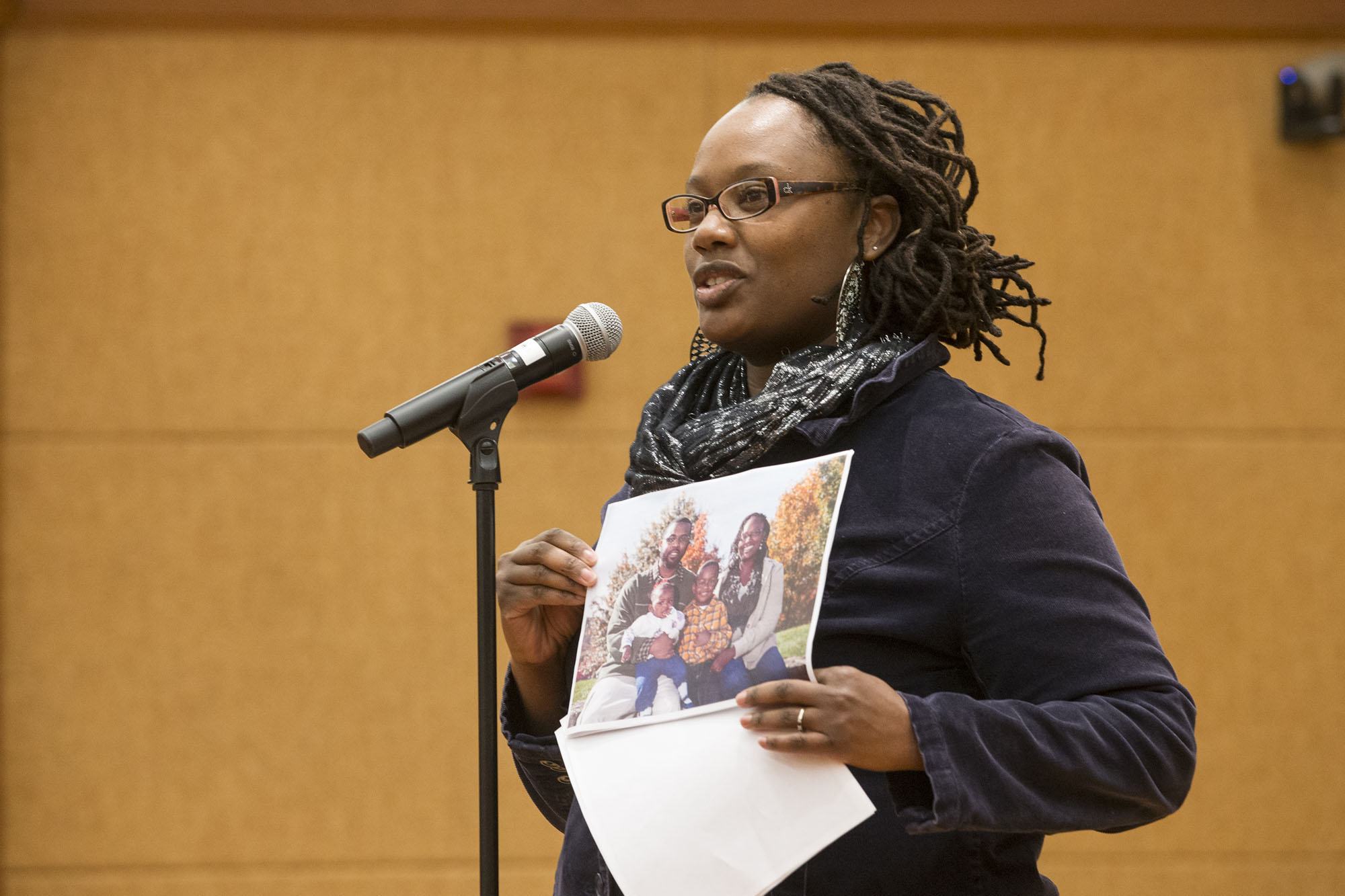 Tobiya Andrews holding a picture of her family and speaking into a microphone