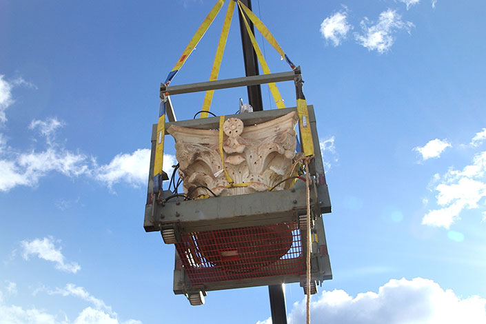 Crane lifting a heavy piece of the top of a pavilion column in the air