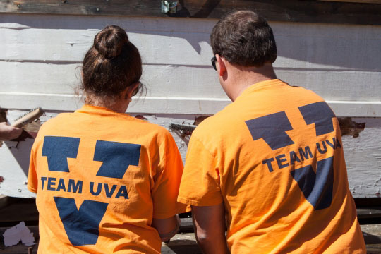 Two UVA team members working together to repaint a building