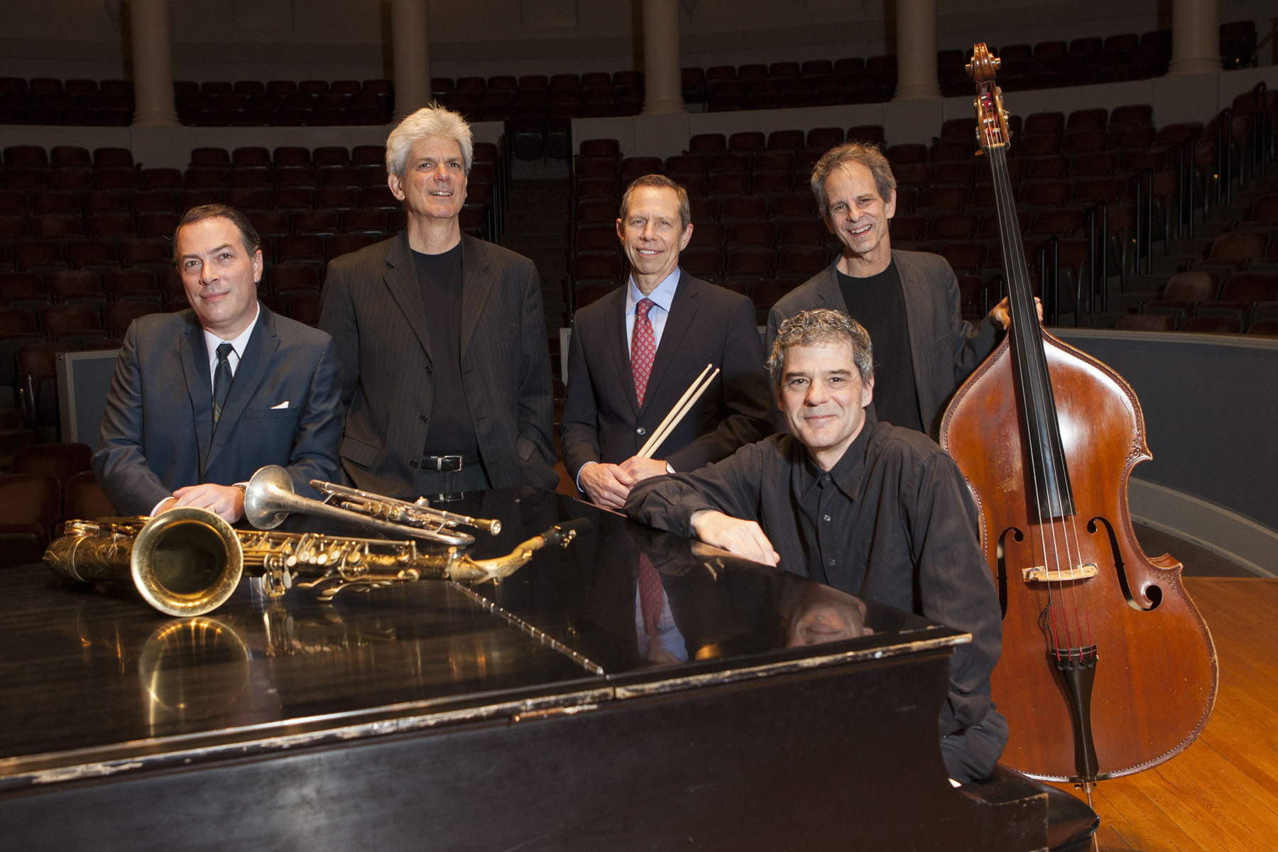Free Bridge Quintet surround a piano while smiling at the camera for a group photo