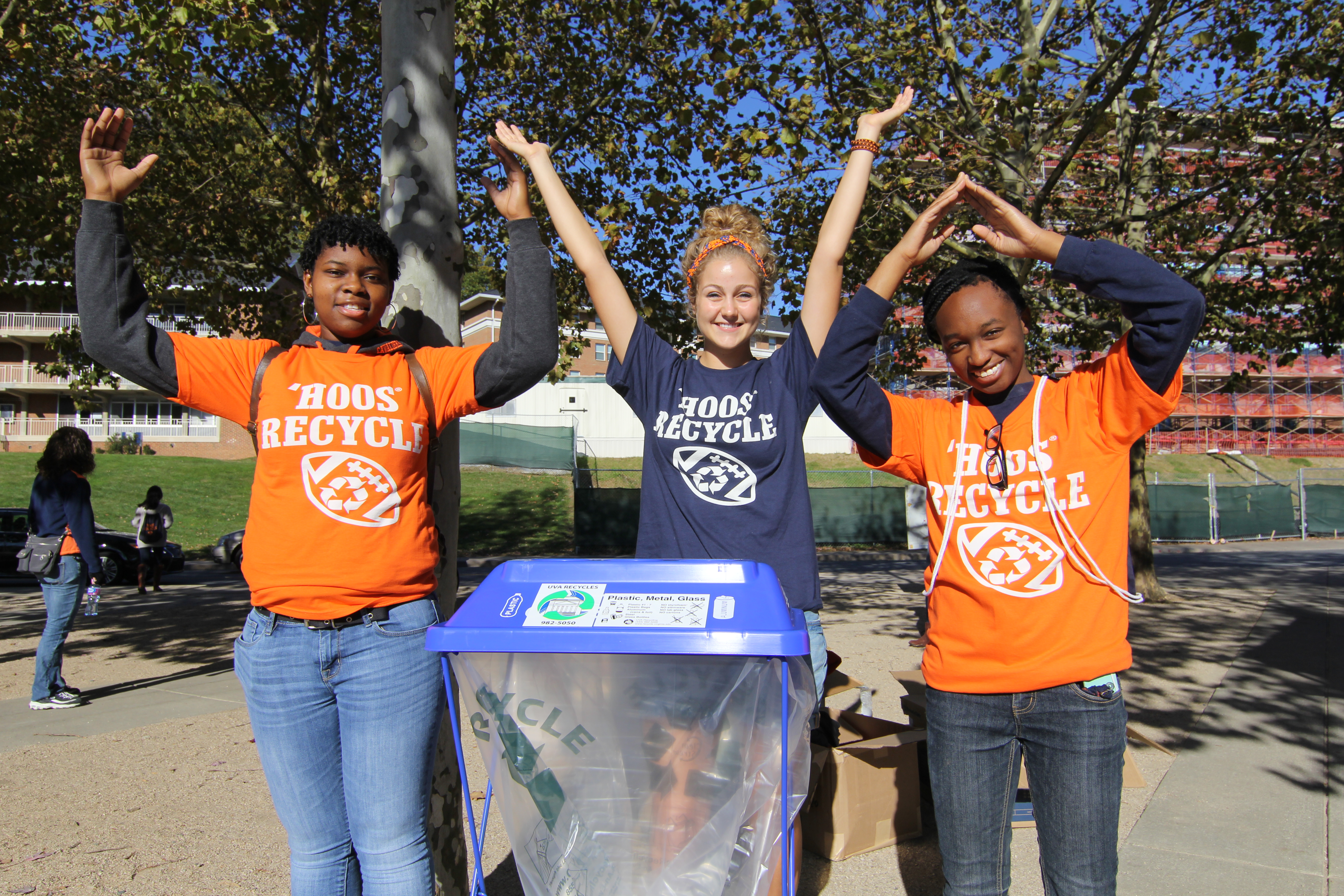 Three UVA students spell UVA with their arms at a recycling station