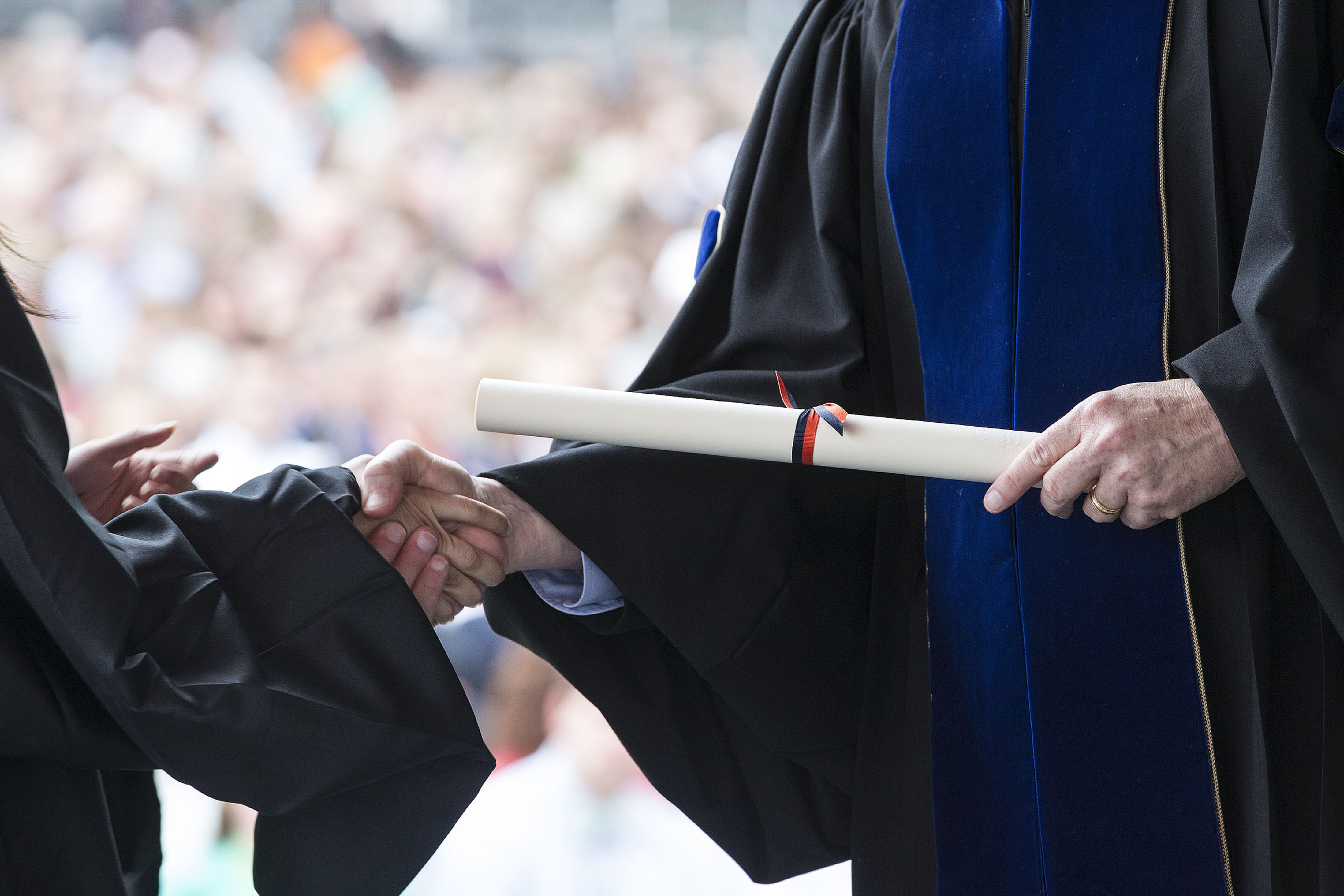 President shaking a students hand handing them a degree