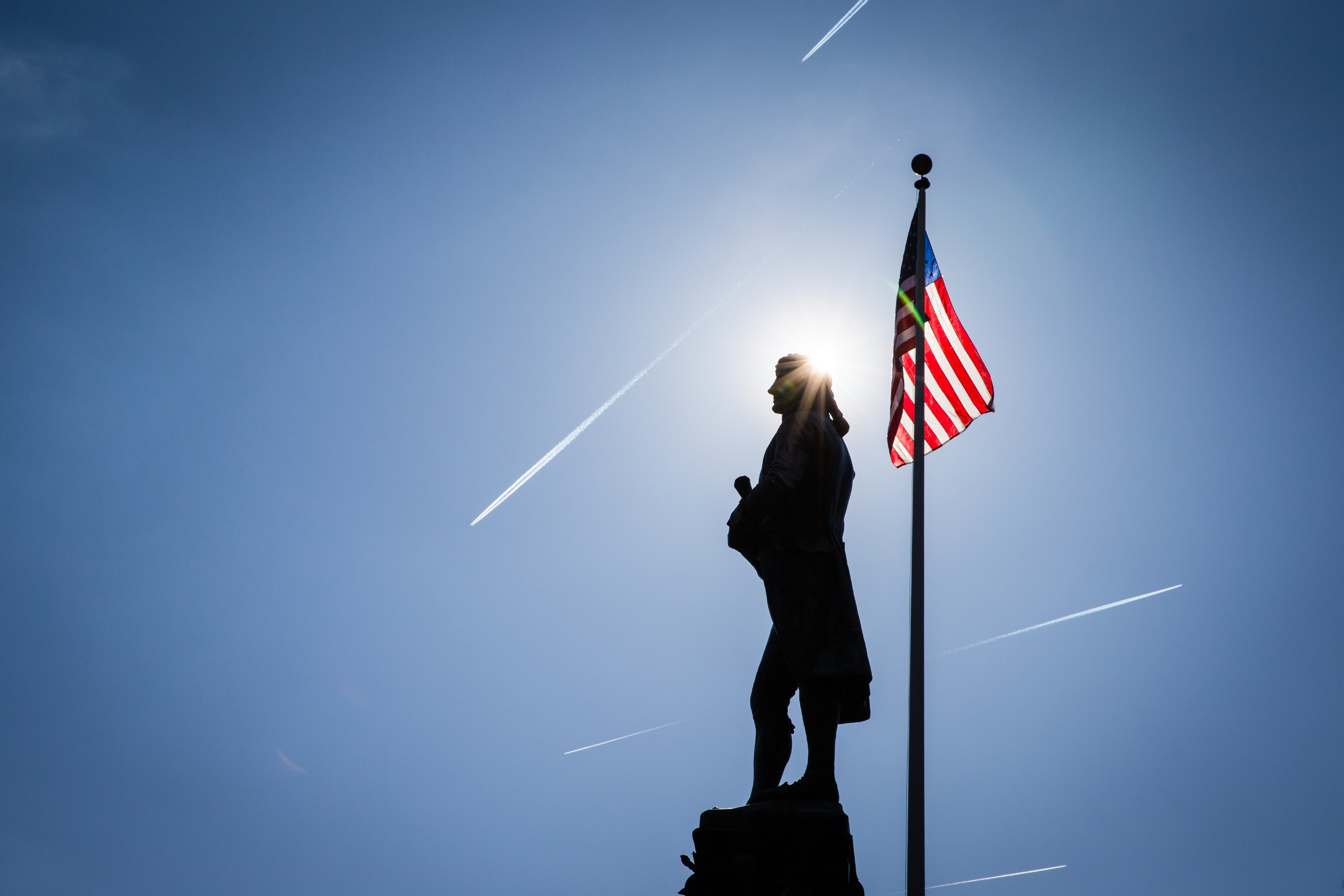 Thomas Jefferson statue silhouette with an American flag behind them and 5 planes in the sky 