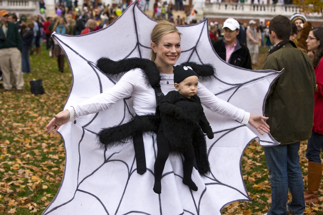 Woman dressed up as a spider web holding her baby who is dressed up as a spider