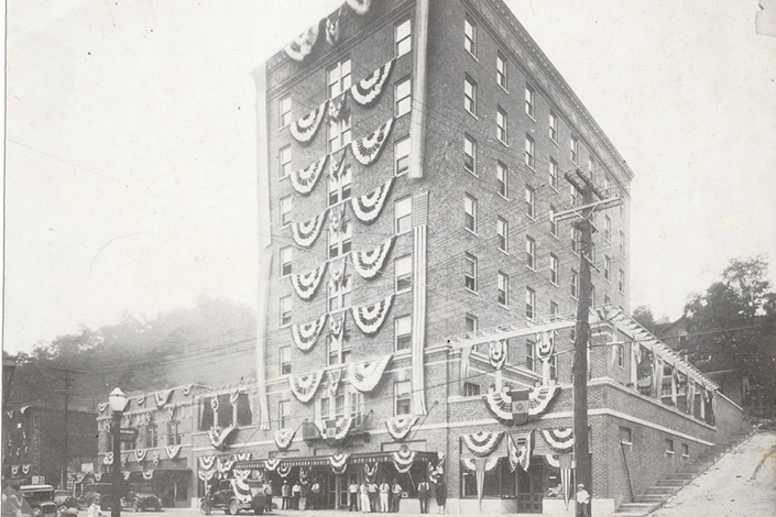 Black and White multistory building with Ruffled horizontal banners hanging on each floor.
