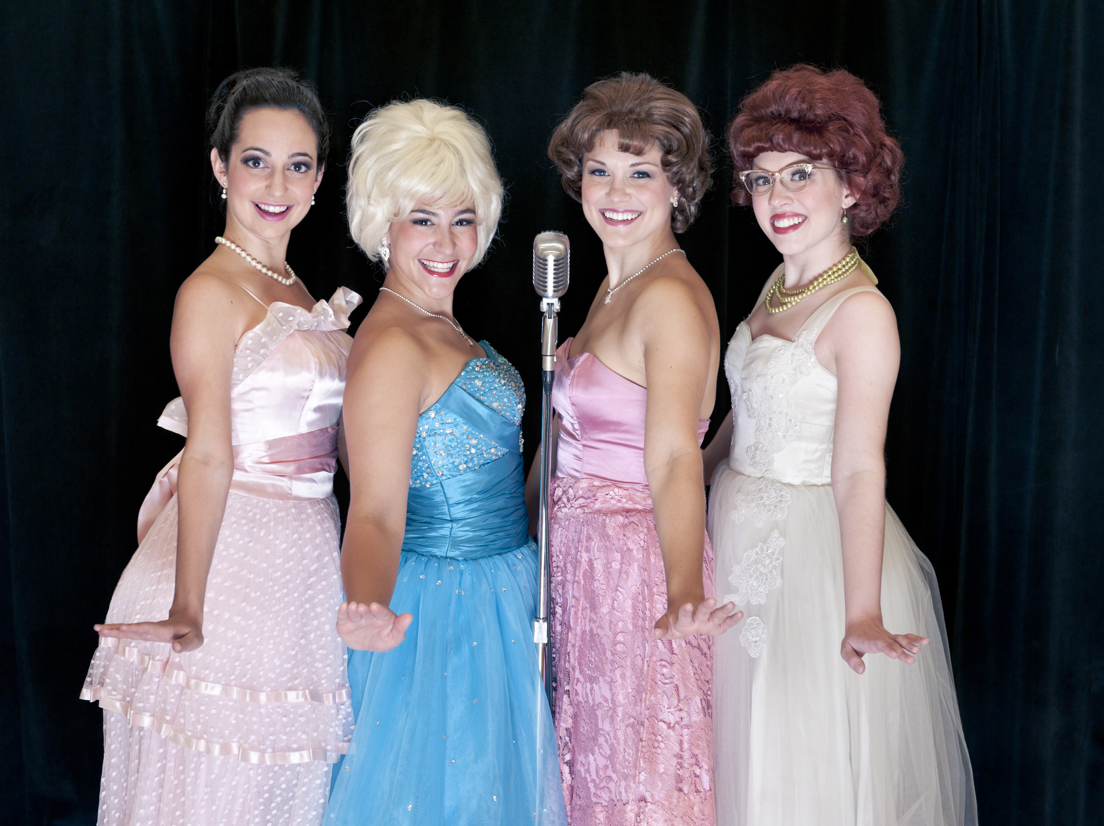 Betty Jean (Ali Stoner), Suzy (Emily Via), Cindy Lou (Emelie Faith Thompson), and Missy (Carly Hueston Amburn) stand at a microphone preparing to sing