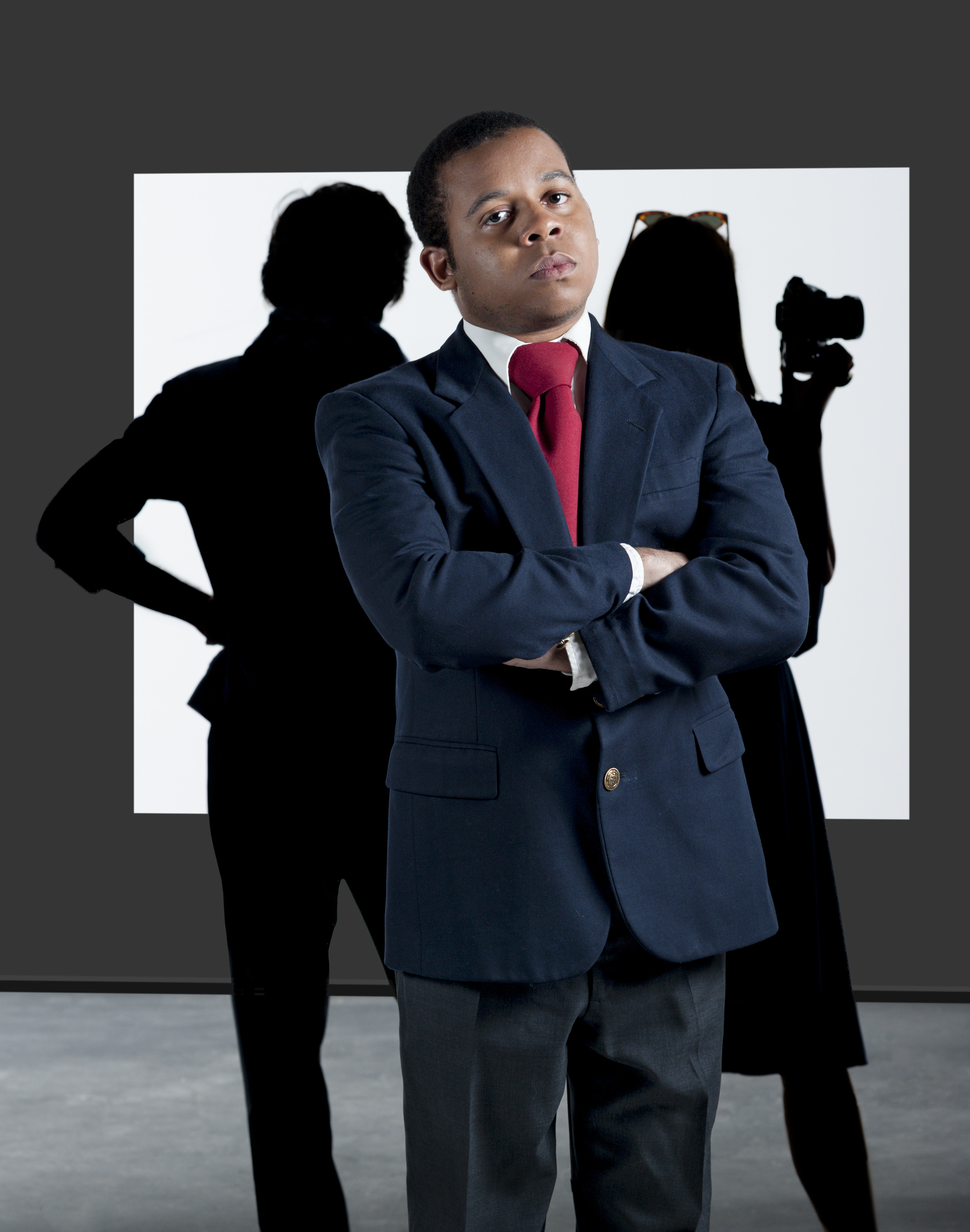 Phillip Rodgers dressed in a suit with two silhouettes behind him
