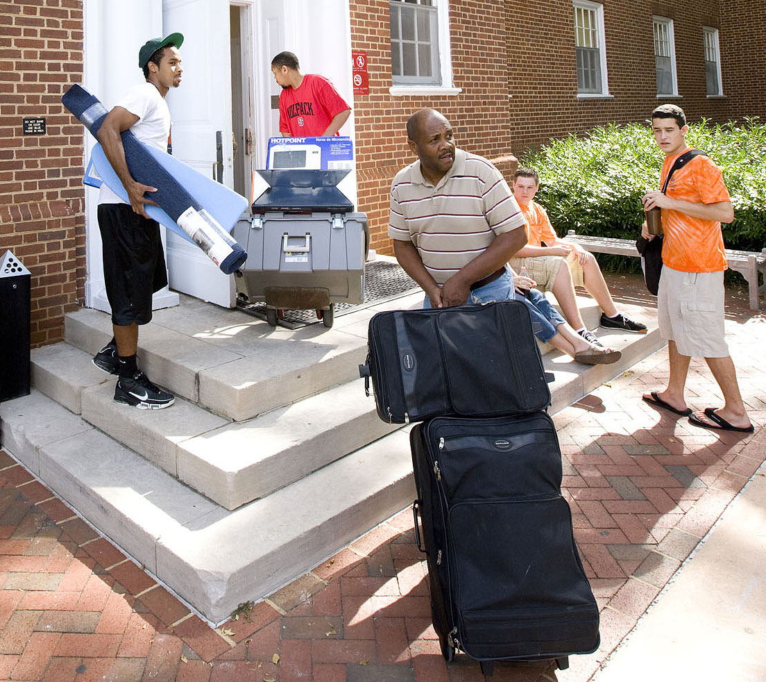 First year students and families carrying their personal belongings into a dorm
