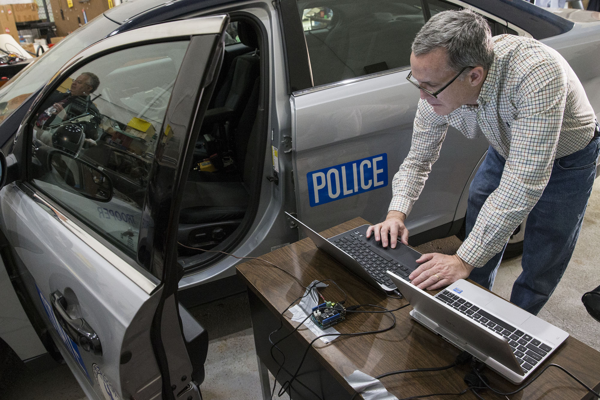 Gary Huband connects two laptops to a Virginia State Police Cruiser