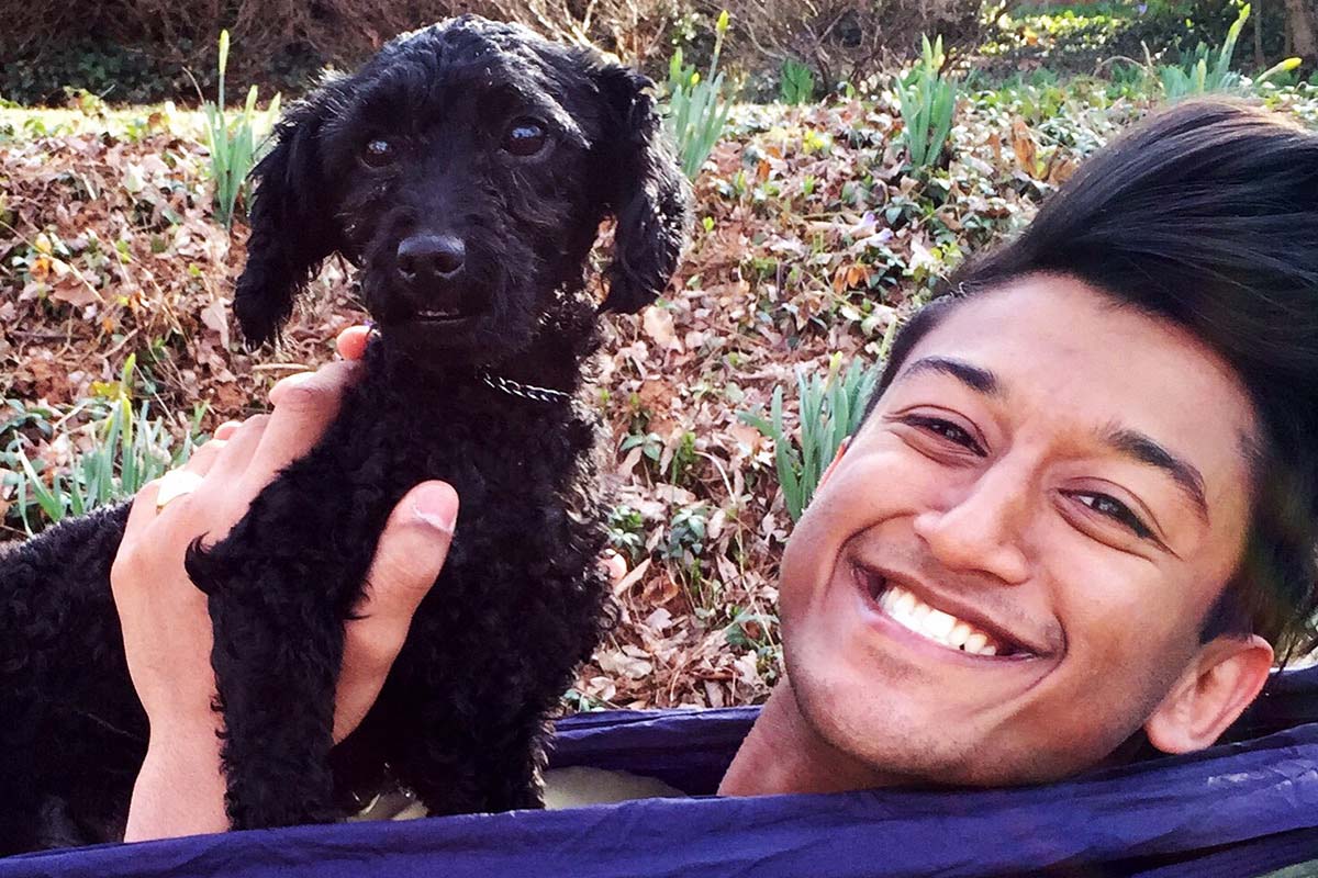 Khan holding a little black dog smiling at the camera