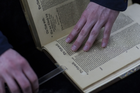 Person clipping a book open to scan its page contents