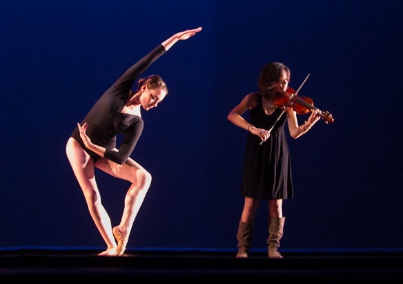 Two women performing on stage.  Woman left is dancing and woman right is playing the violin