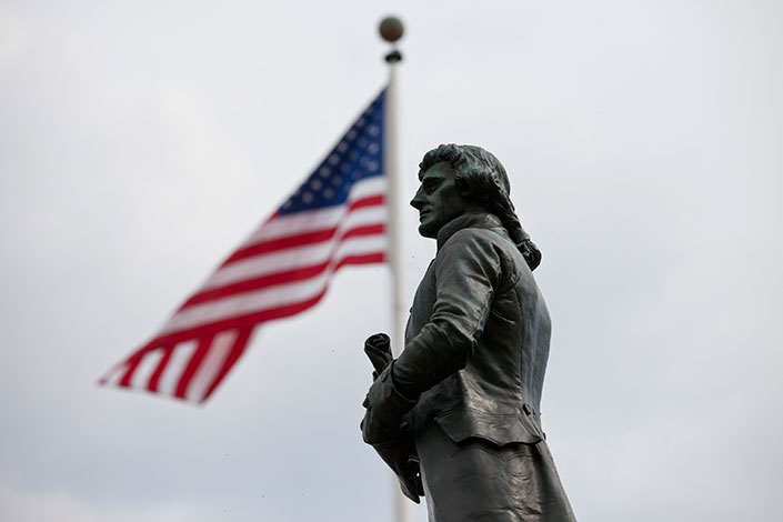 Thomas Jefferson Statue with an American Flag flying behind him on a flagpole