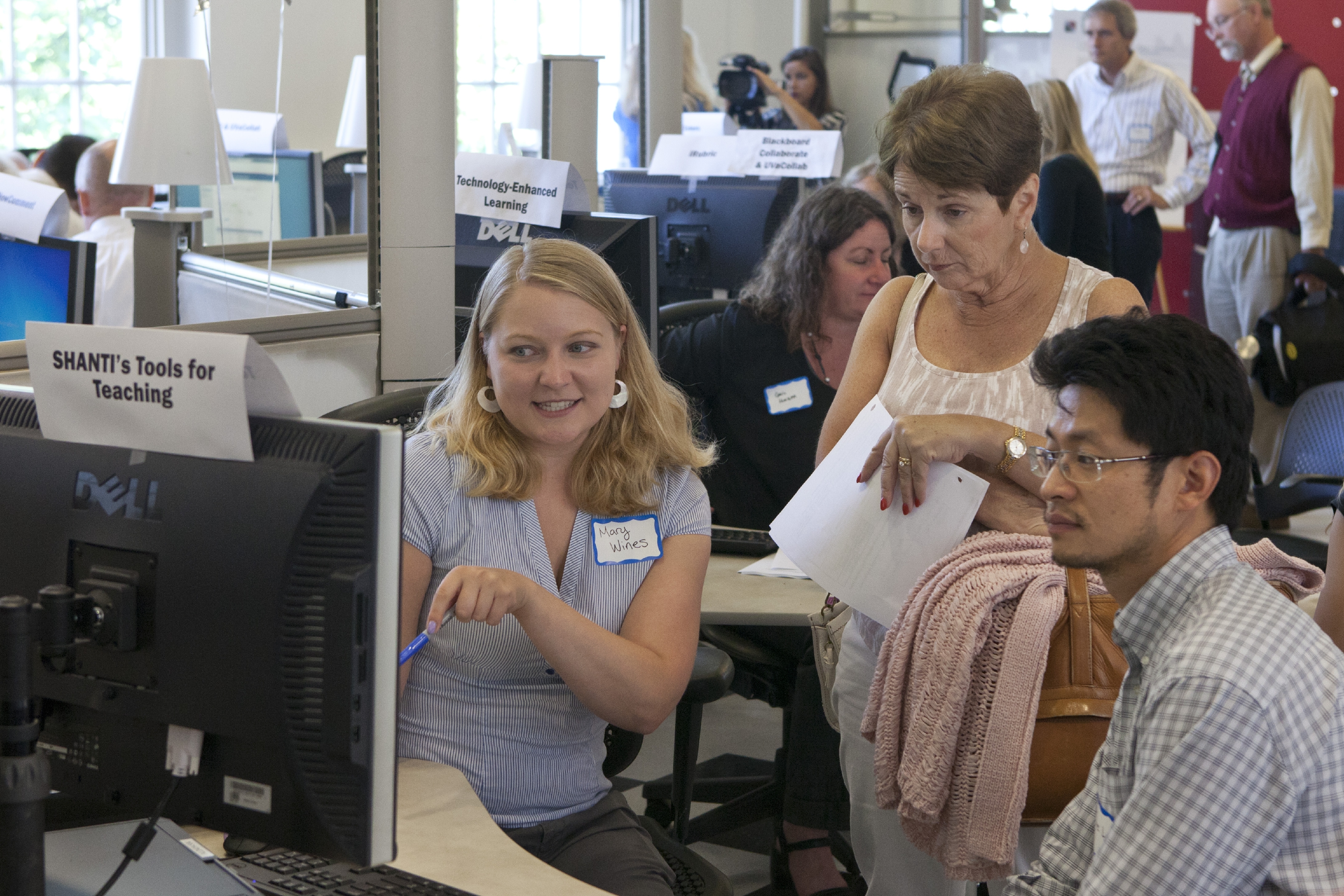 Students talking to an elderly woman at a computer