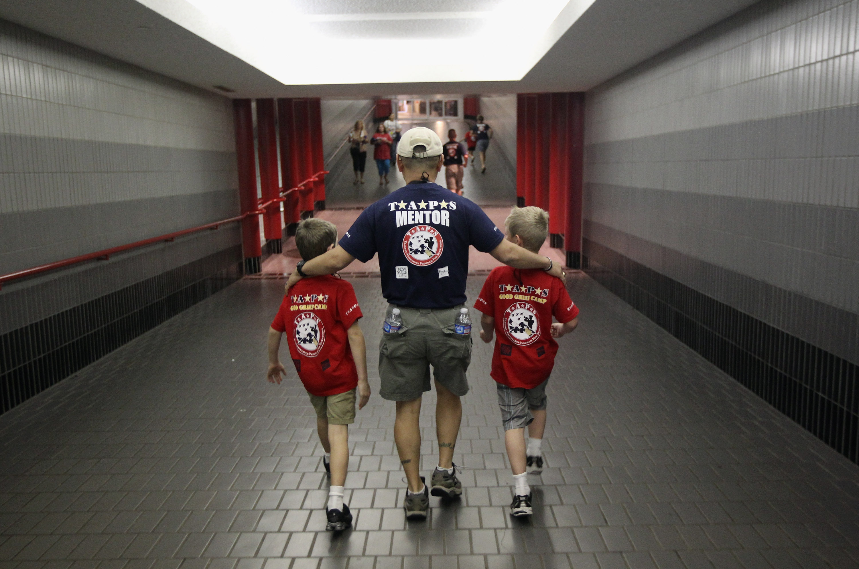 Man wraps his arms around two little boys shoulders while they walk down a ramp
