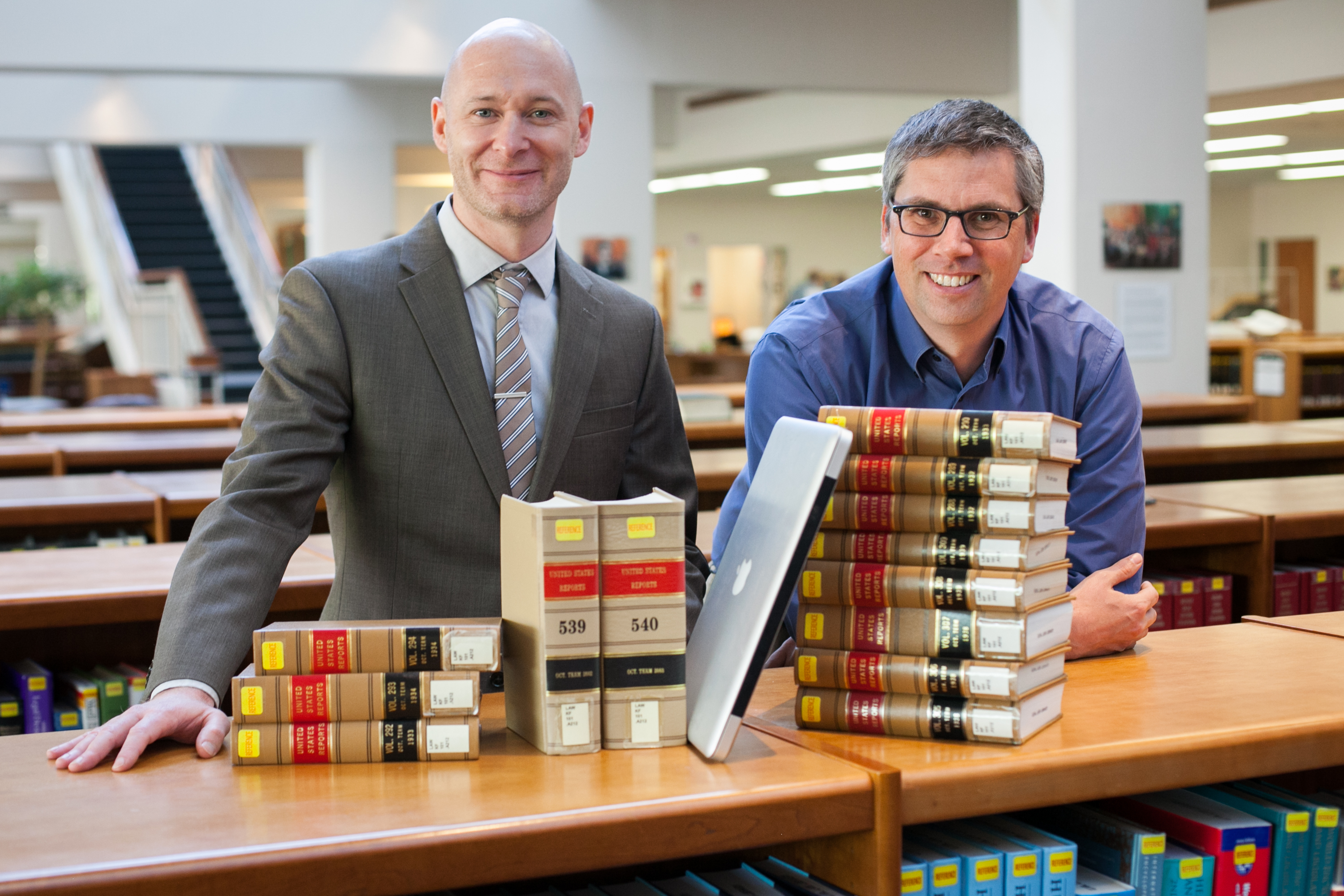Michael Livermore, left, and Jon Ashley, stand with a stack of books and a computer