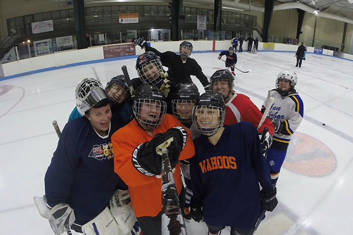 group of students wearing hocky masks standing on the ice for a picture