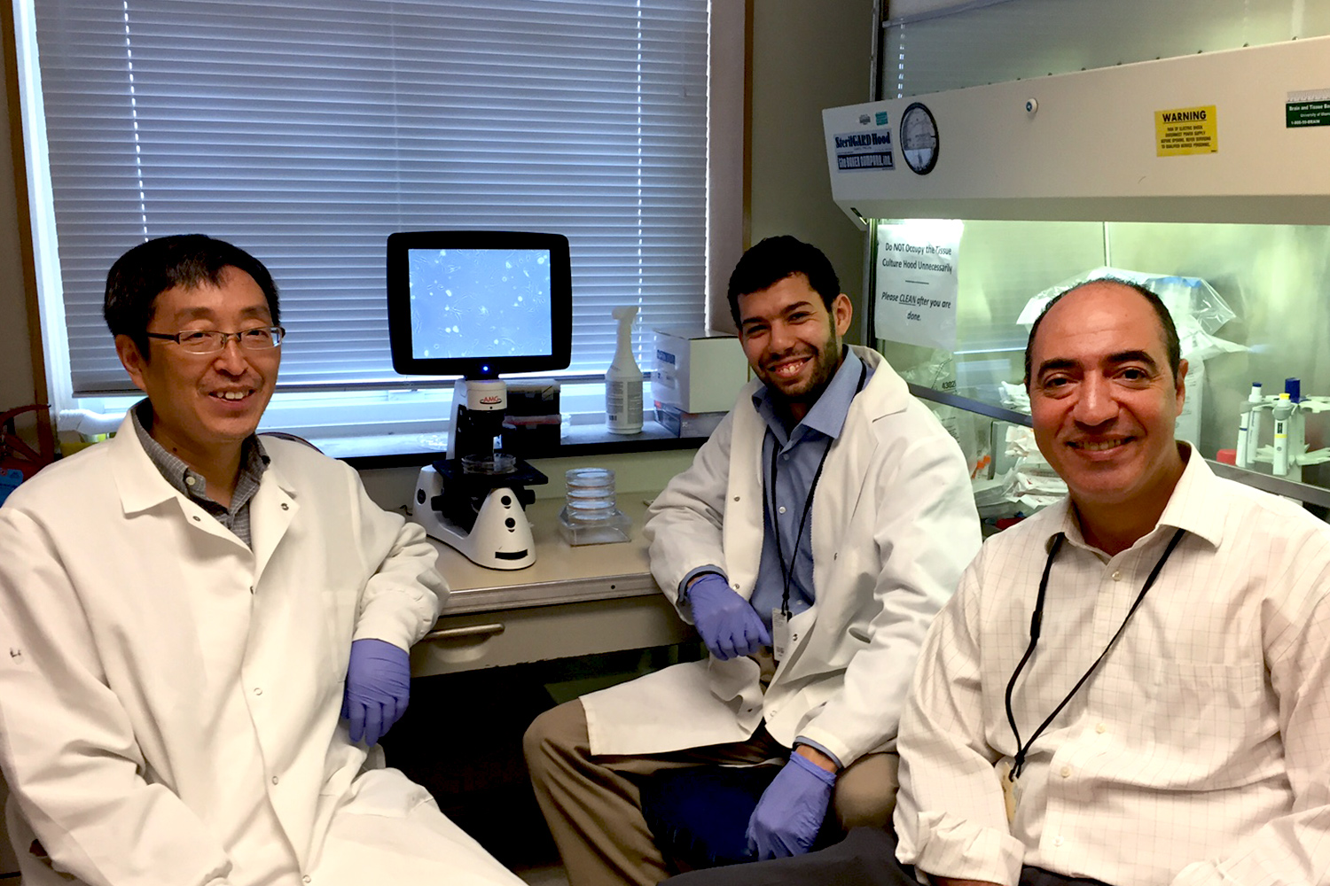 From left, Kangping Du, Mouadh Benamar, and Tarek Abbas sit in chairs in a lab smiling at the camera