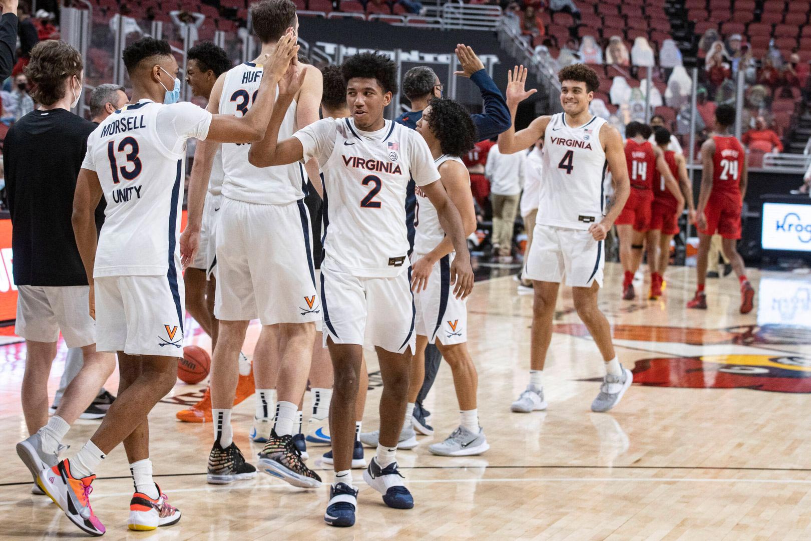 UVA basketball players exchanging high fives on the court after a victory against Louisvile