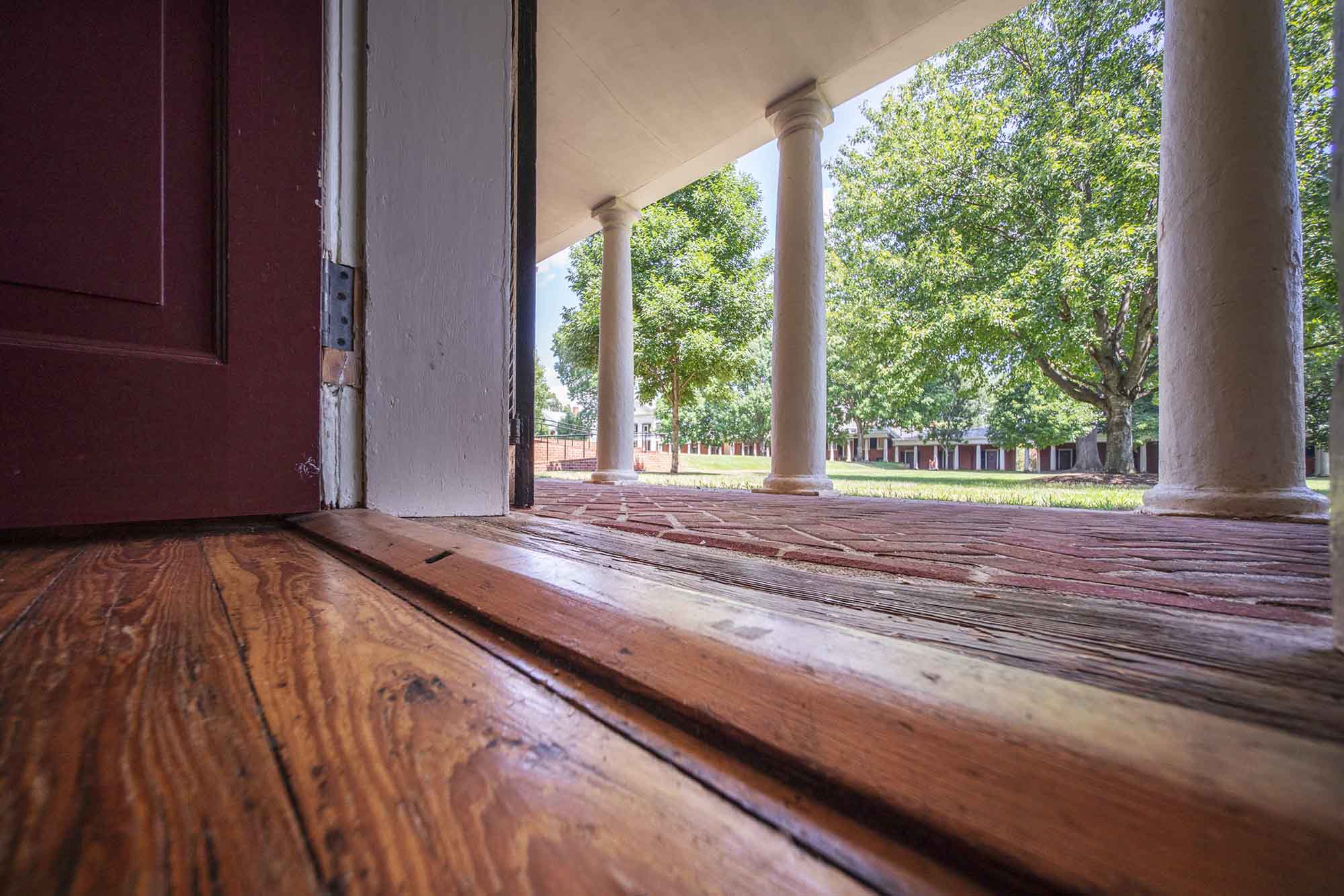 Wood floor at the entrance of the Lawn room facing the outside to the brick walkway in front