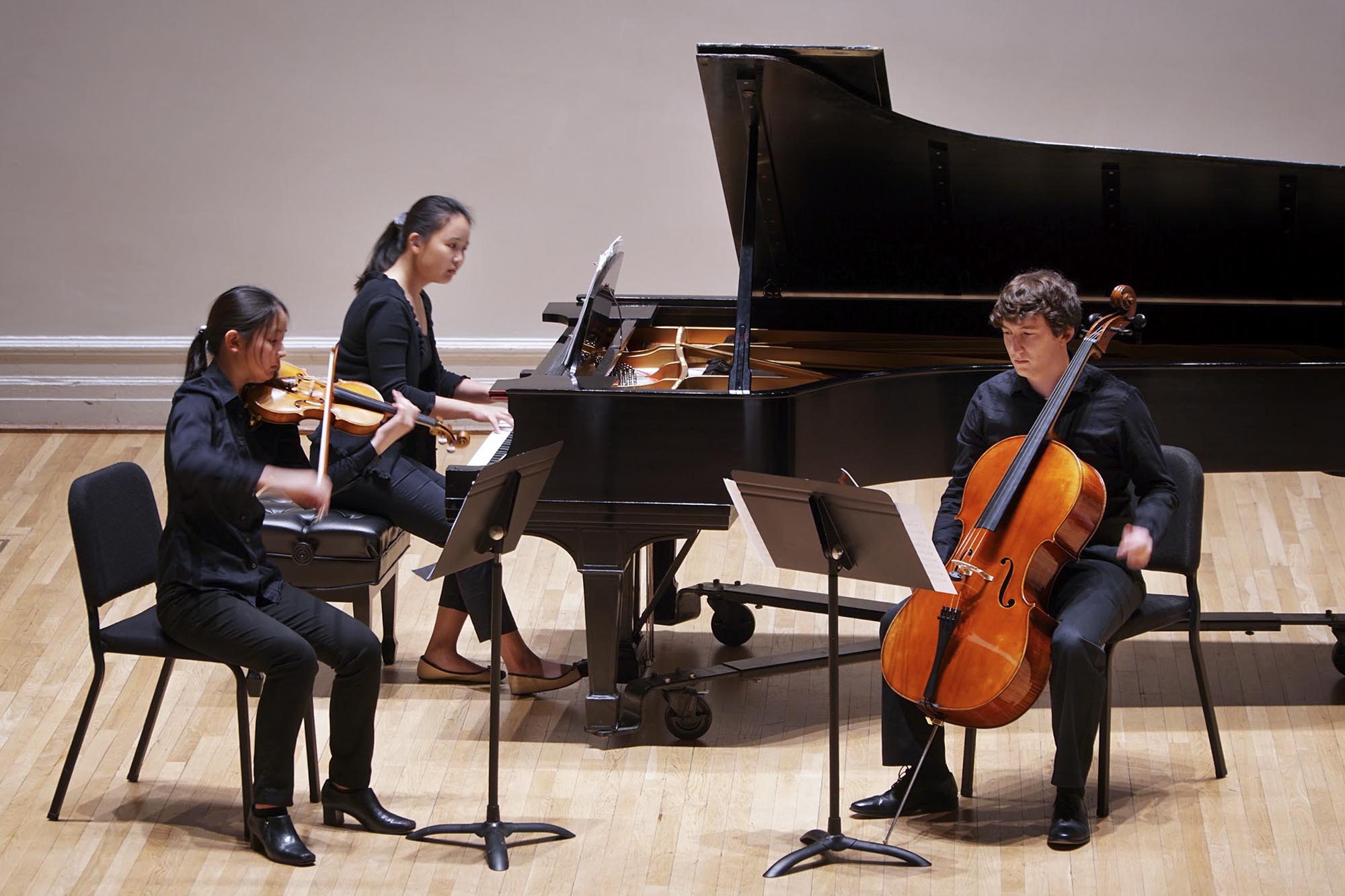 Sophia Park, Anna Wang and Brent Davis  play their musical instruments on a stage
