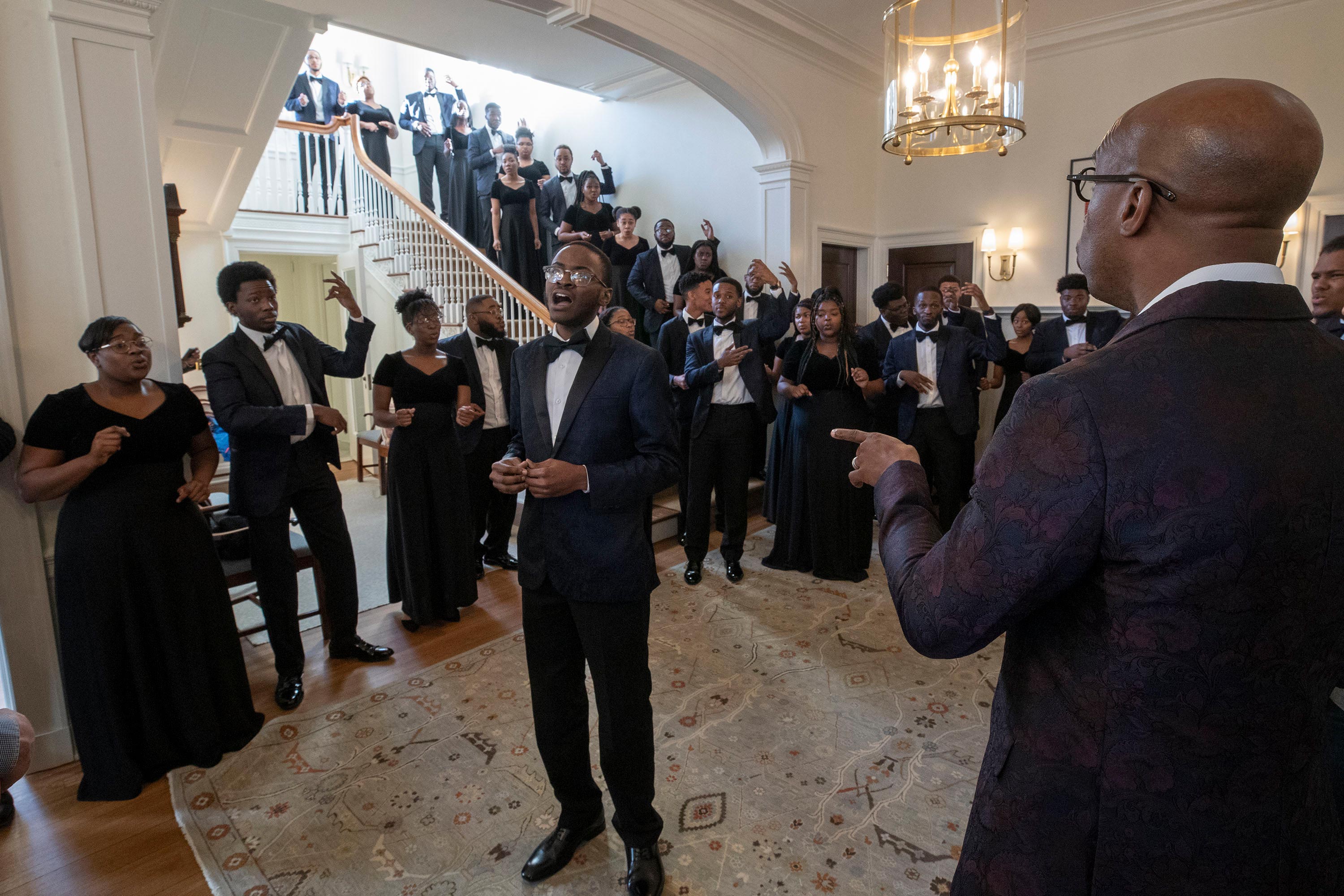 The Aeolians  standing in a hall wall and on the stairs dressed in black and white singing