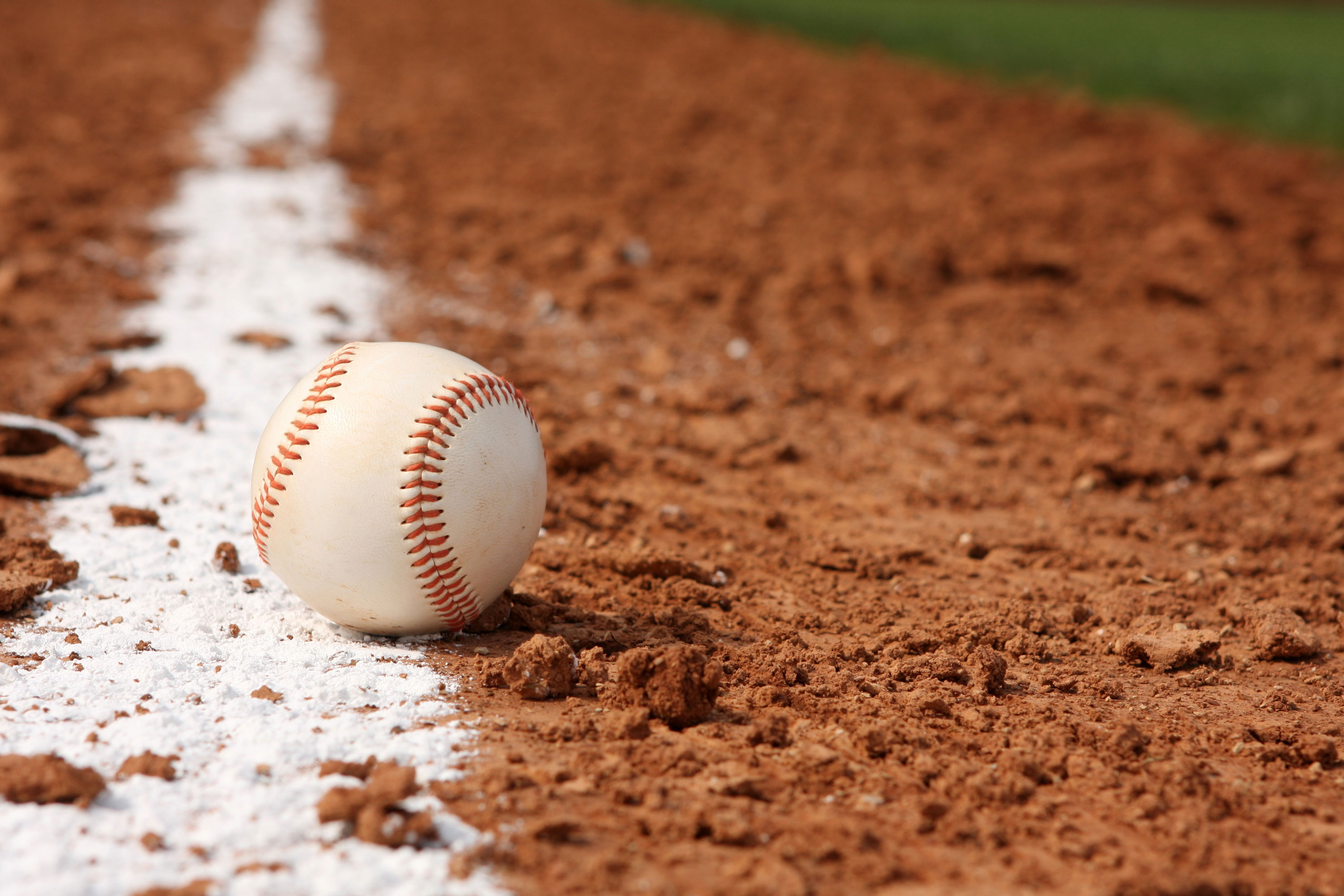 Baseball sits on the dirt touching the white line