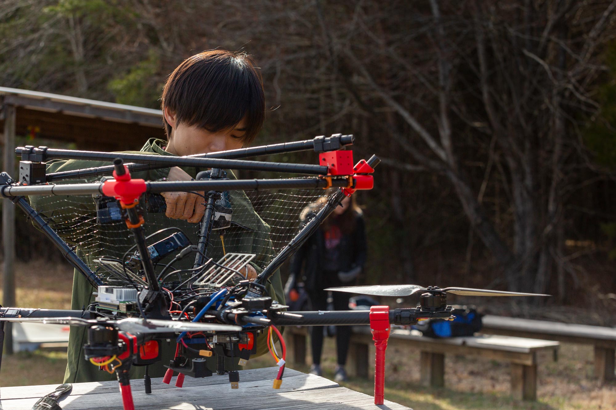 A student from Team VICTOR works on an aerial drone on a table