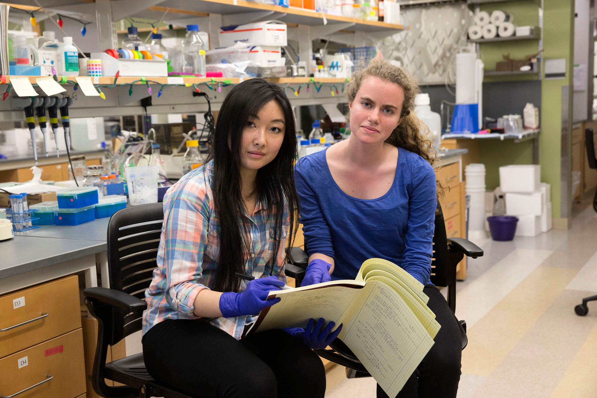 Lucy Jin, left, and Ana Untaroiu, right,  sit in two lab chairs reviewing notes